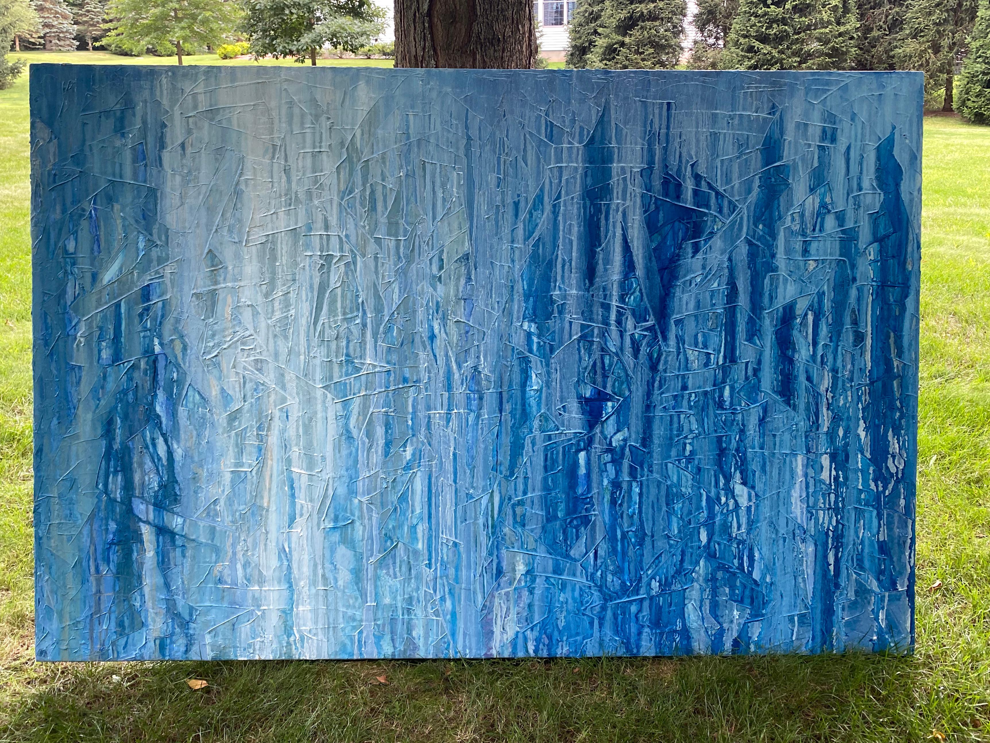 Questo grande quadro astratto di Teodora Guererra è caratterizzato da una tavolozza blu e bianca. La pittura sembra gocciolare su uno strato inferiore strutturato del dipinto. È stato realizzato con pittura a olio su tela da galleria e presenta lati