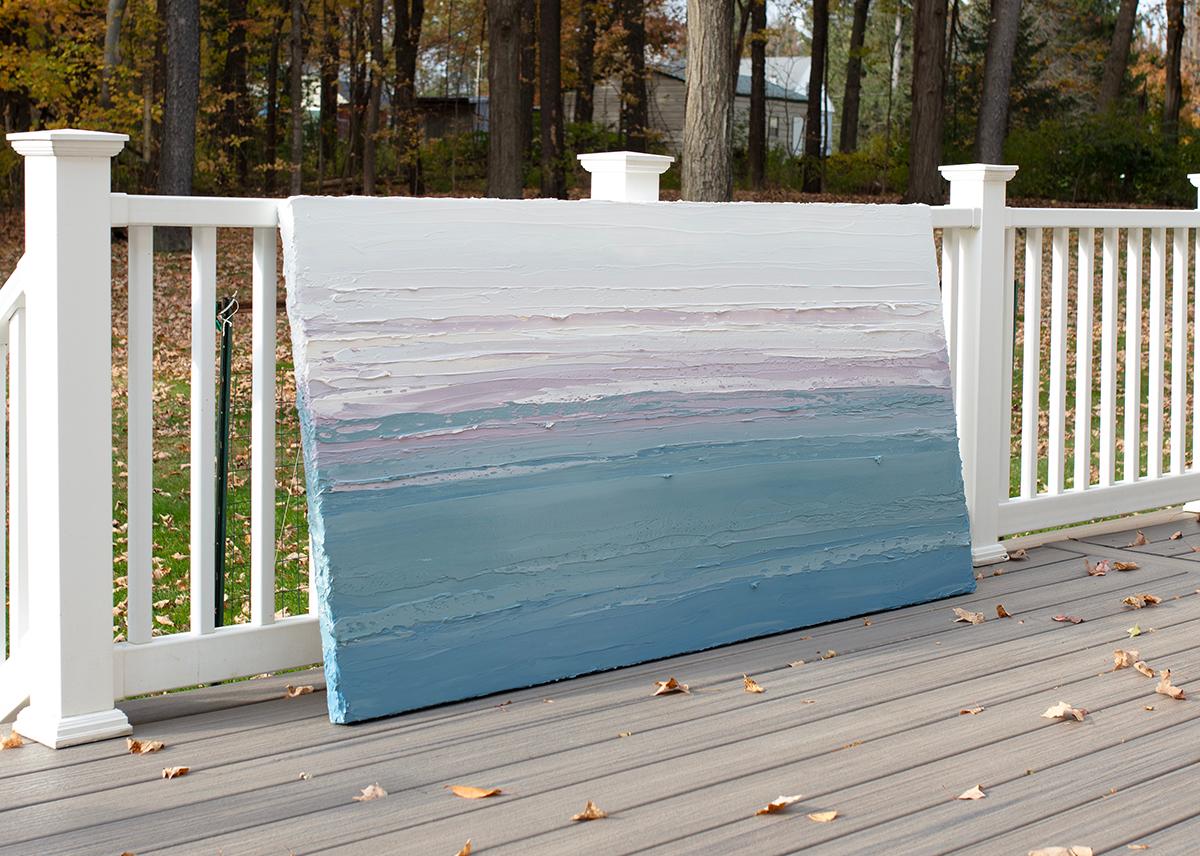 Questo quadro astratto orizzontale di Teodora Guererra è caratterizzato da una tavolozza di blu, verde acqua, lavanda e bianco. L'artista stende spesse pennellate di colore con una spatola in ampie pennellate orizzontali su una tela avvolta in una
