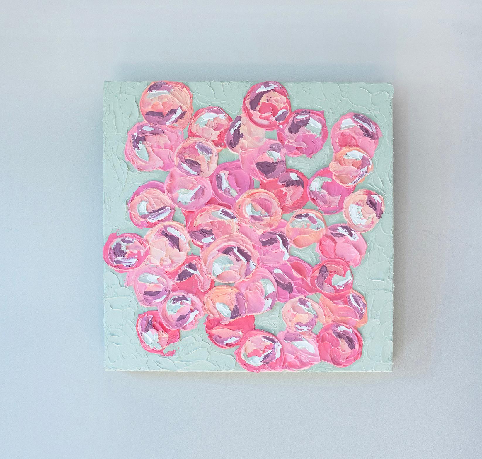 This original painting by Teodora Guererra features a pink and green palette with circular, abstracted pink floral shapes assembled at the center of the composition on a pale green background. The artist applies thick layers of paint on the canvas