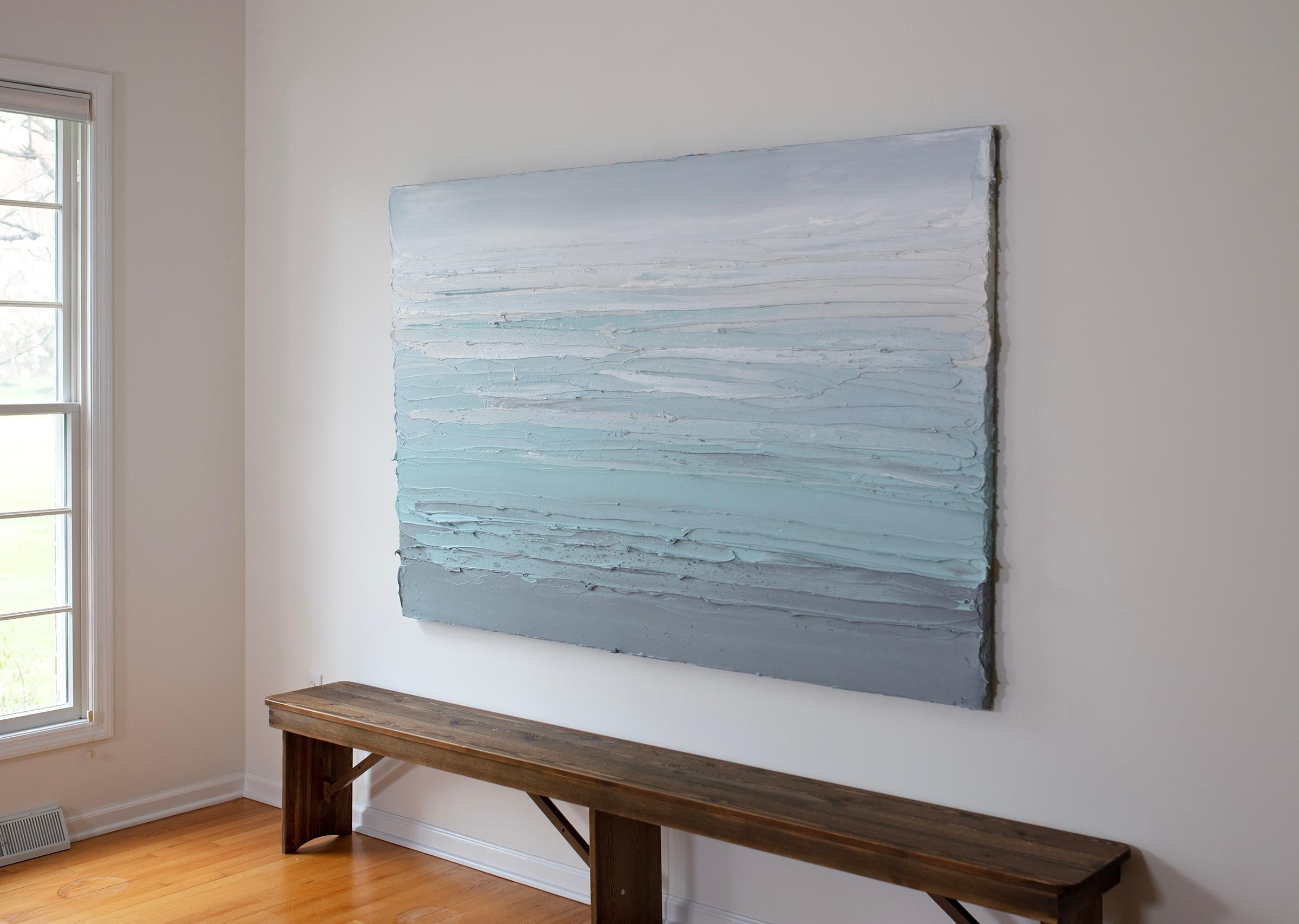 Ce grand tableau abstrait de Teodora Guererra présente une palette côtière légère de bleu, de gris clair et de blanc. L'artiste applique d'épaisses couches de peinture en faisant de larges gestes horizontaux pour créer une surface épaisse et