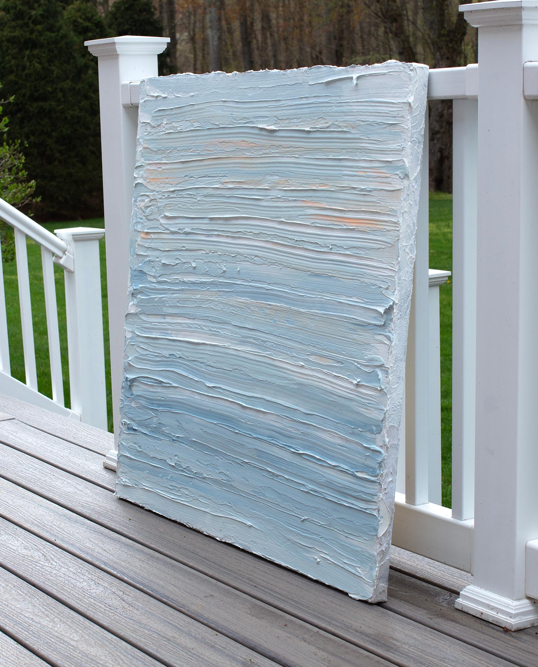 Cette peinture abstraite de Teodora Guererra présente une palette légère et froide de bleu et de blanc avec de subtils accents d'orange en haut de la composition. L'artiste applique d'épaisses couches de peinture à l'huile dans des gestes larges et