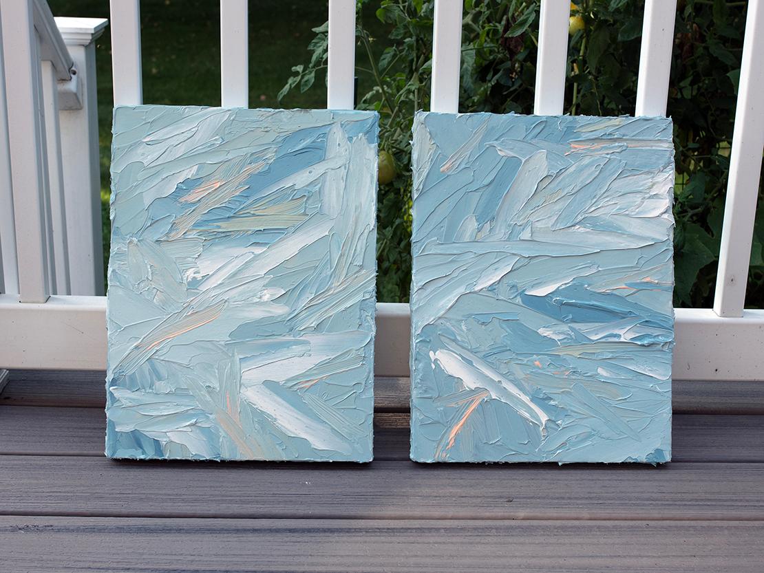 This textured abstract diptych by Teodora Guererra features a light blue-green palette with warm yellow accents throughout. The artist layers thick strokes of paint using a palette knife over board, creating an abstract composition and highly