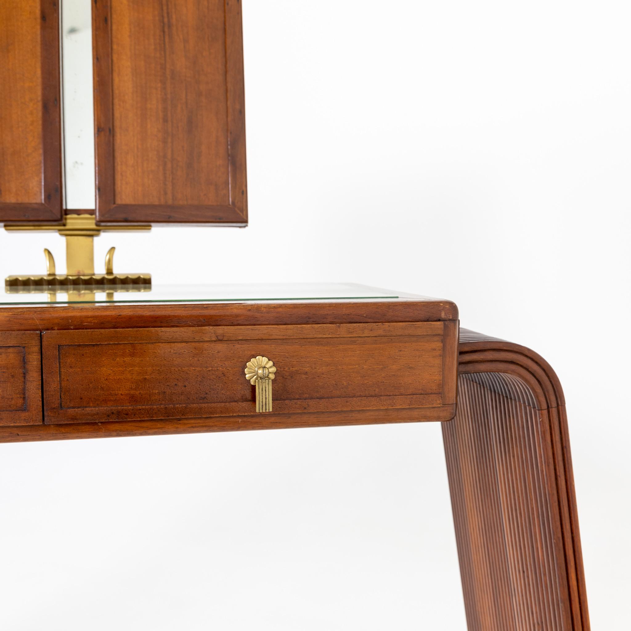Art Deco dressing table or vanity with two drawers and swivelling, three-piece and folding mirror by Teonesto Deabate. The dressing table stands on grooved side pieces and is inlaid with a gold coloured glass top.