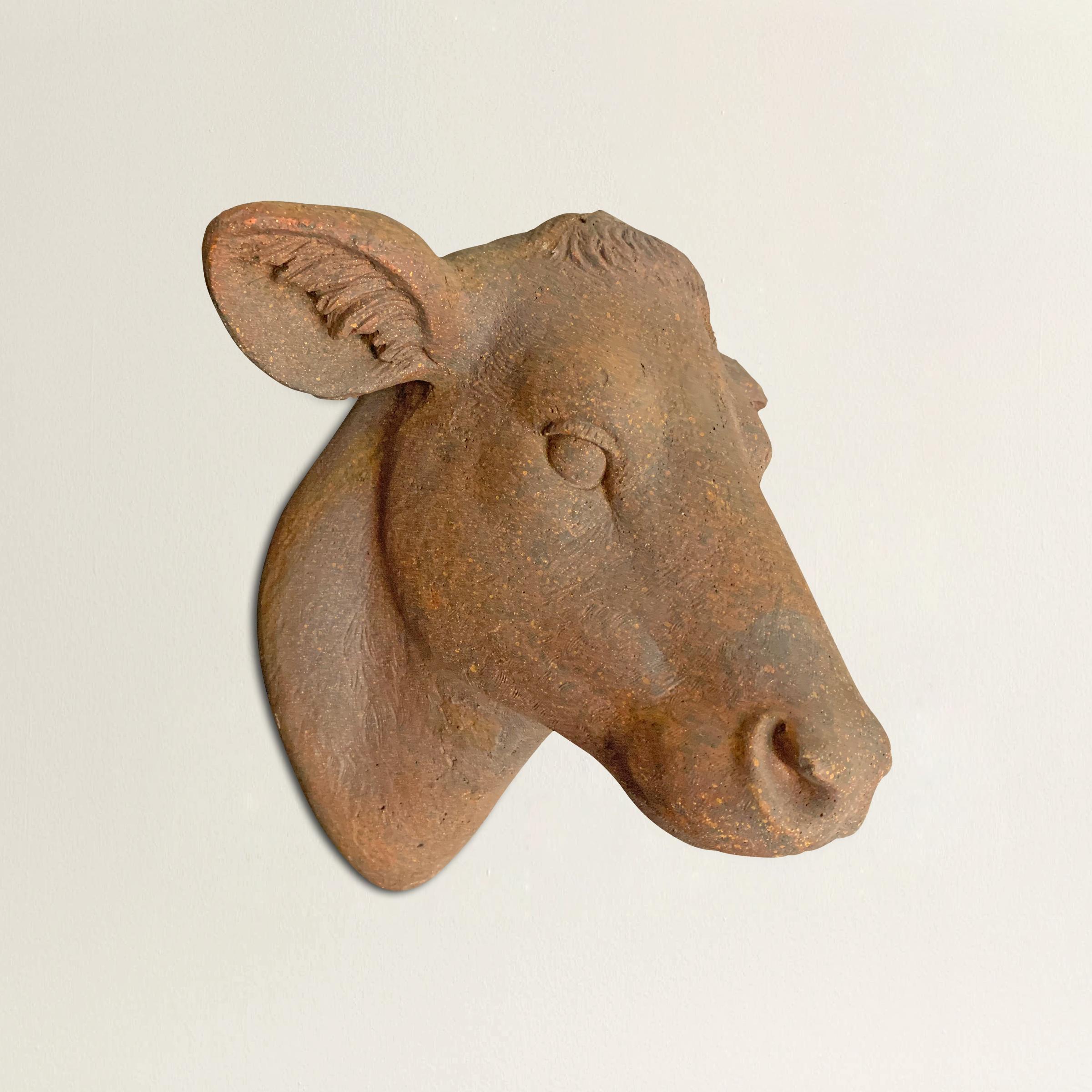 A wonderful and whimsical American terracotta cow head reminiscent of antique French butcher's shop signs. Mounts to a wall with an attached ring in the back.