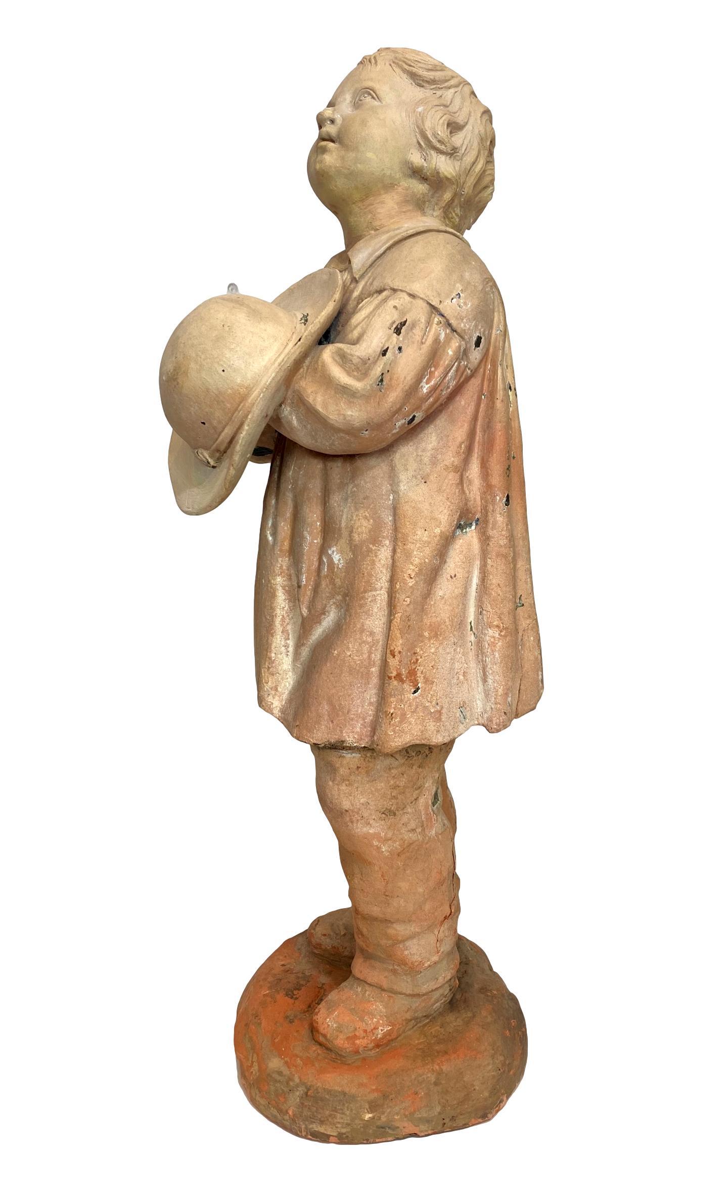Charming terra cotta figure of a boy with hat, staring into the heavens, French, ca. 1890. Measures: 21 inches high.