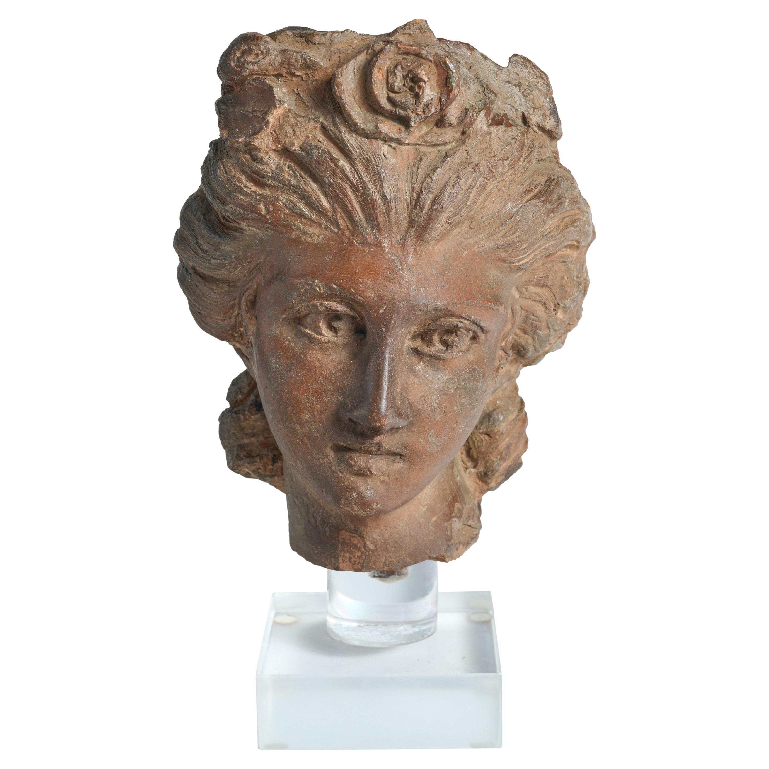 Fragment de statue en terre cuite représentant une tête de femme classique