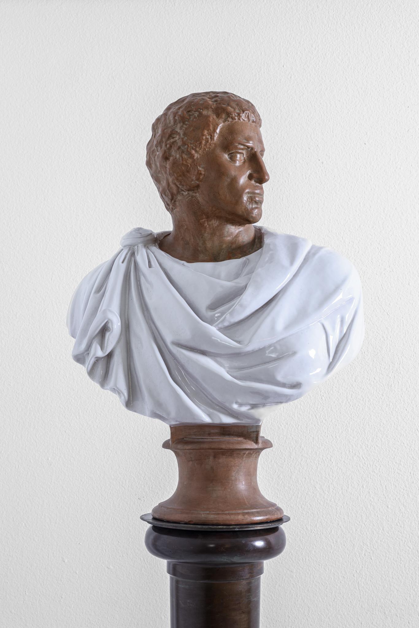 This terra-cotta sculpture no doubt depicts the bust of Roman Emperor or Senator in classical dress gazing over his left shoulder. This is a magnificently robust life size bust. His robe has been fired in a white glaze. The bust has a 7
