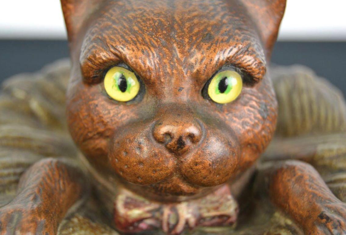 Terracotta Cat Tobacco jar. 
A Tobacco jar - humidor with a cat or puss on top of the lid. 
This tobacco jar in the shape of a barrel looks great ! 
The cat who peeps out of the barrel has yellow glass eyes, wears a bow around the neck and leans on