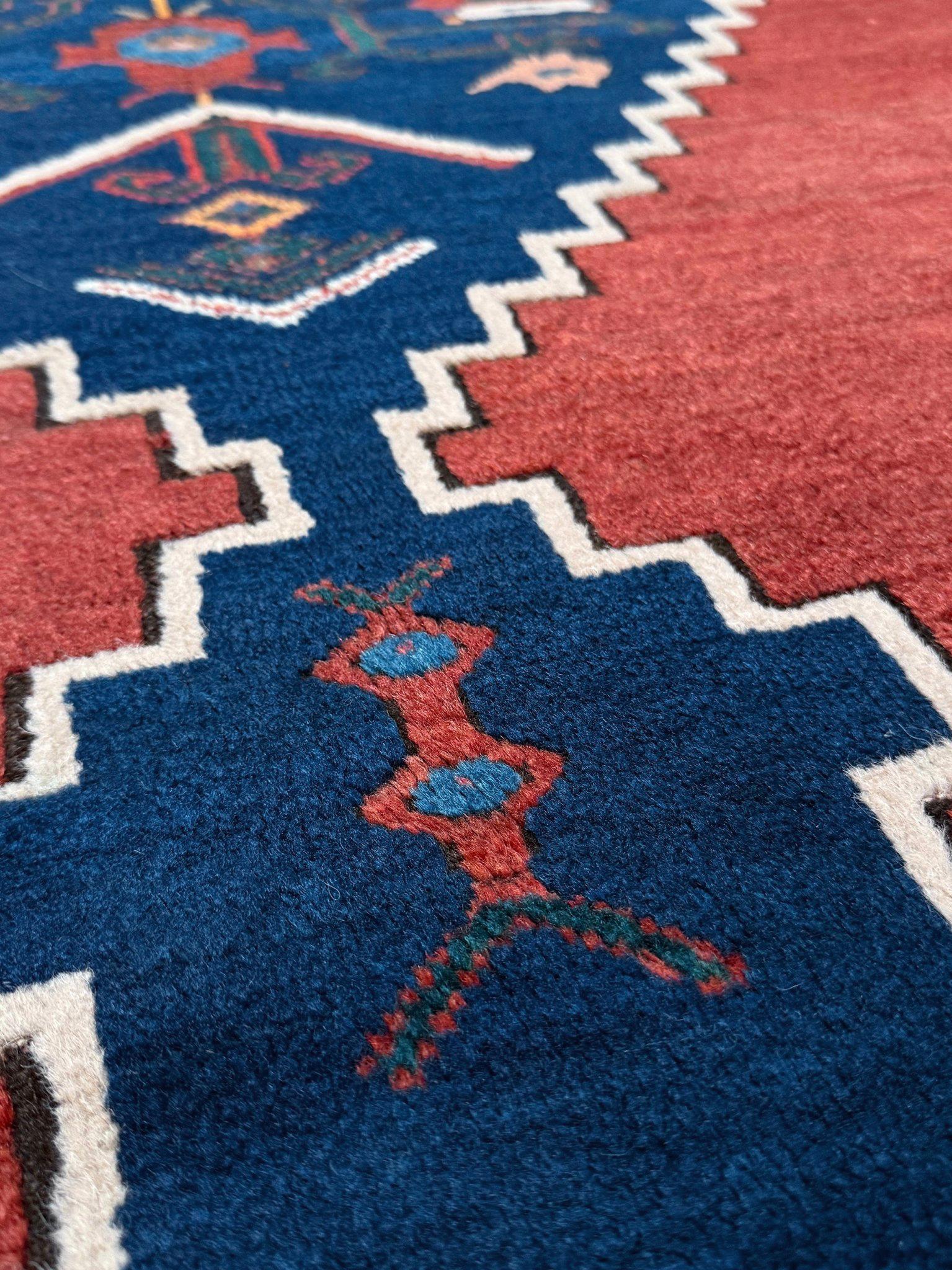 Esempio di artigianato caucasico dei primi del Novecento, questo tappeto semi-antico conferisce una geometria audace e una presenza artigianale a qualsiasi spazio. Tessuta a mano negli anni '30, presenta uno scenografico medaglione blu notte a