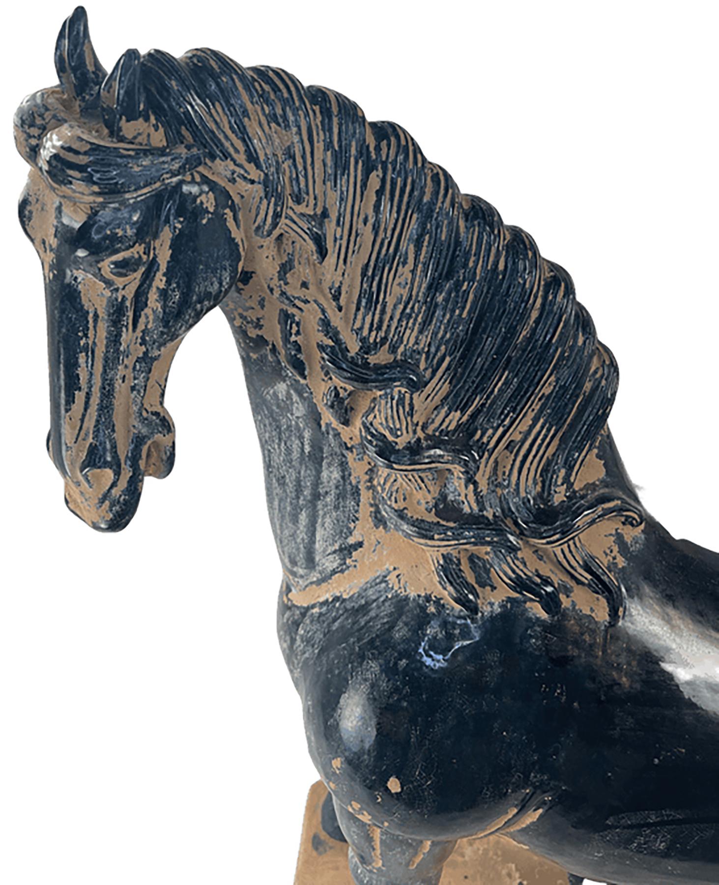 A handcrafted terracotta horse in the style of the Tang Dynasty sculptural tradition. 

Much of the body of the piece is glazed with a dark indigo blue finish. Some fading in detailed areas provides visual accent and personality to the piece. The