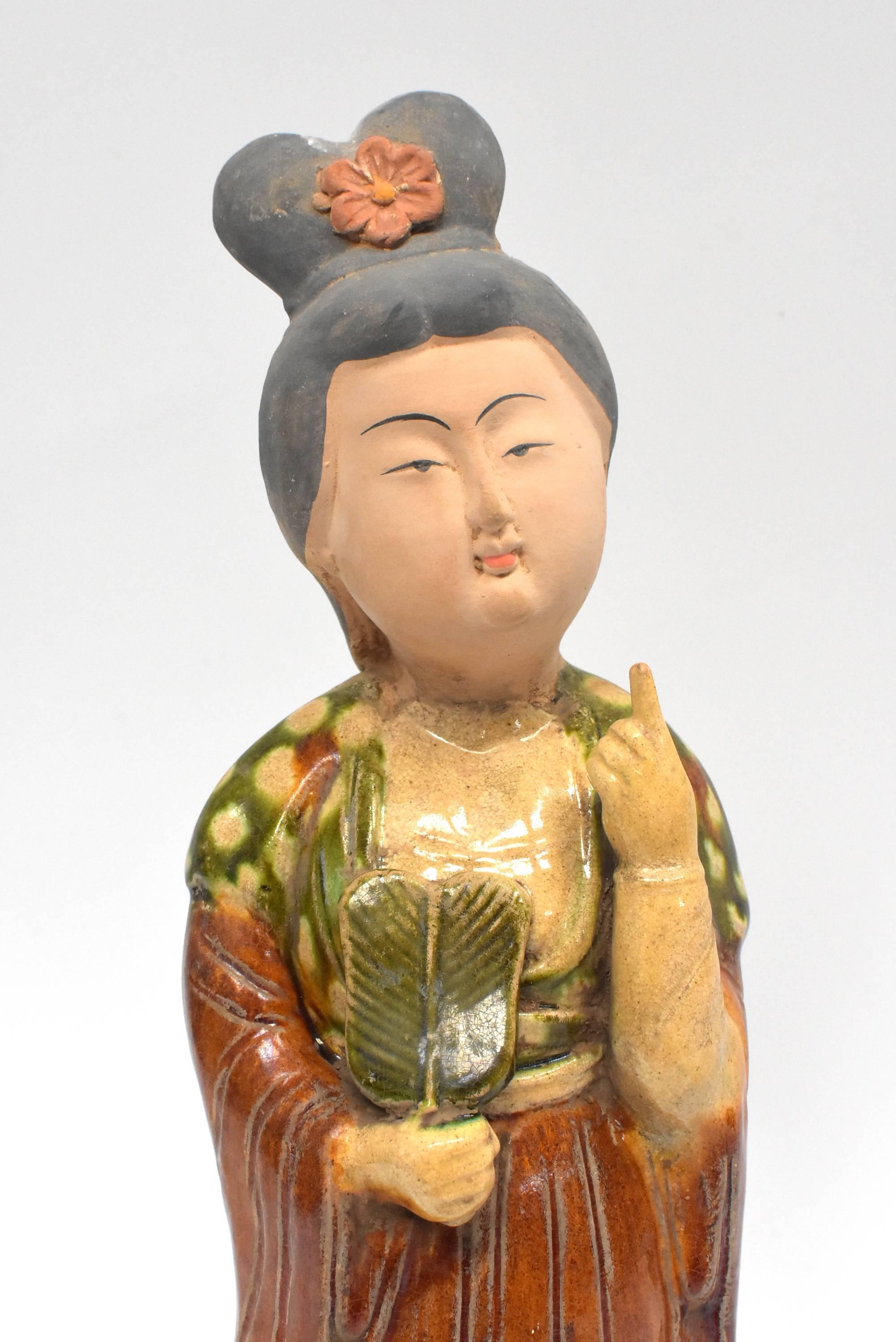 A beautiful terracotta court lady in the Chinese Tang dynasty San Cai style. Fine facial features and traditional dress and hair style. The tri-glaze is the typical green, caramel and beige. The lady's expression is peaceful and serene. Her full