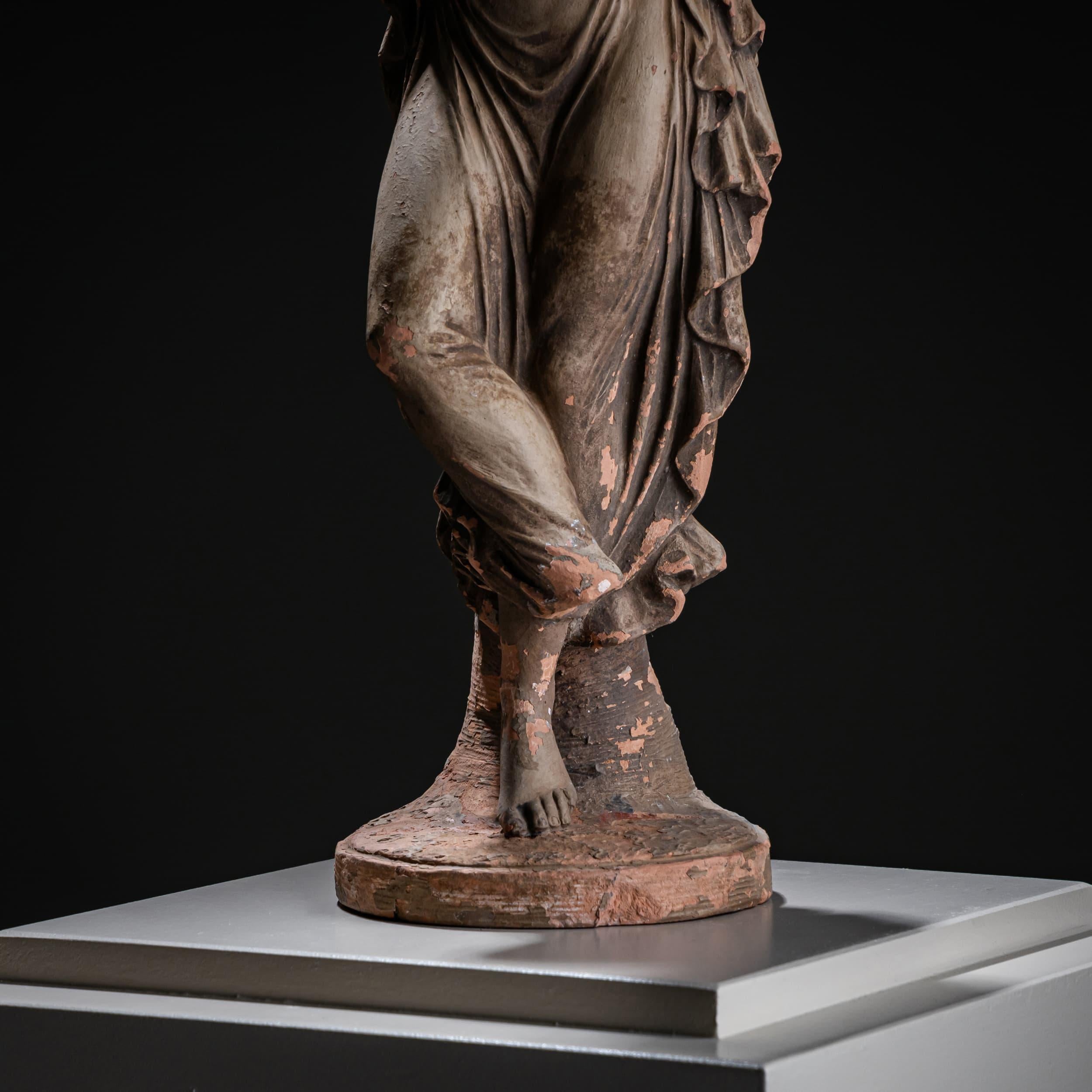 Sculpture en terre cuite d'après l'emblématique Danzatrice con dito al mento (1809-1814) d'Antonio Canova, un exemple magistral de l'élégance néoclassique. La danseuse est capturée dans une pose gracieuse, un doigt pensif posé sur son menton - une