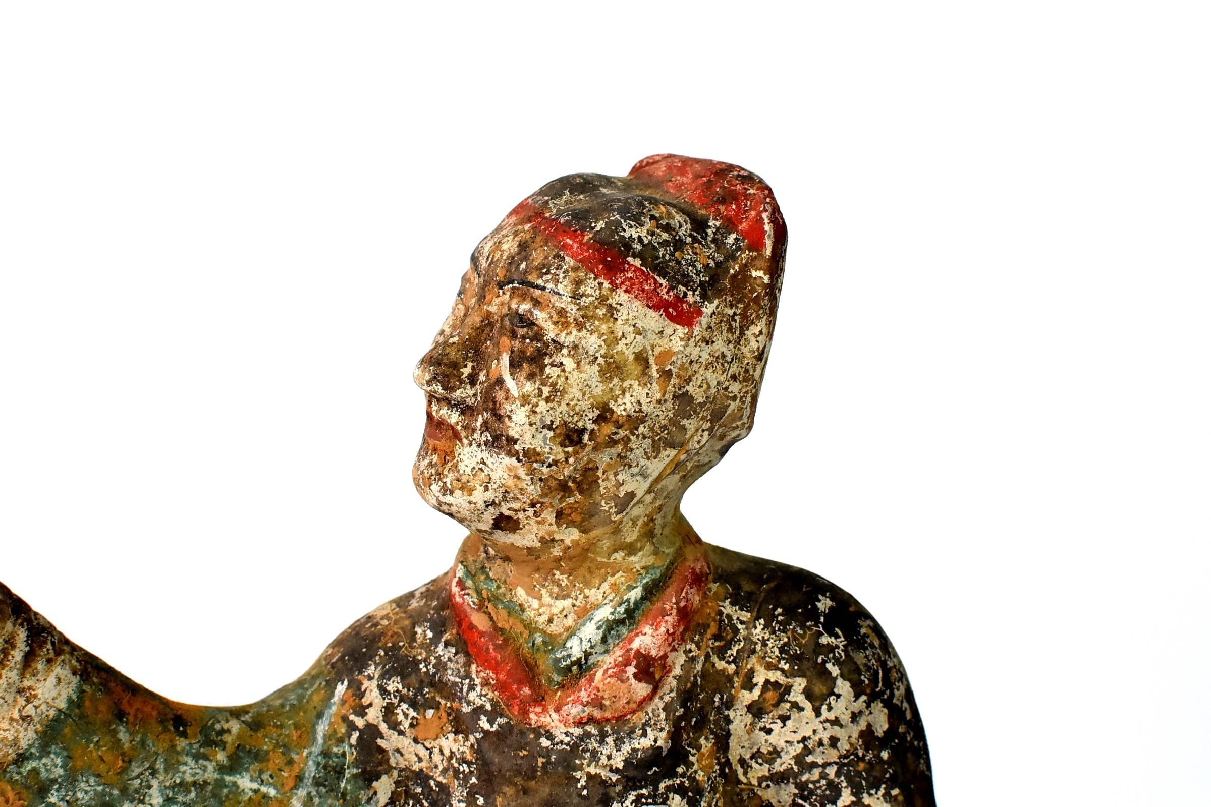 A fantastic Han style terracotta figure. Such a figure is seen in the Han dynasty dating 206 BC to 220 AD. The figure wears a hat and boots, his black robe has red and green stripes. Either a servant or a hostler, such a statue was regarded as a