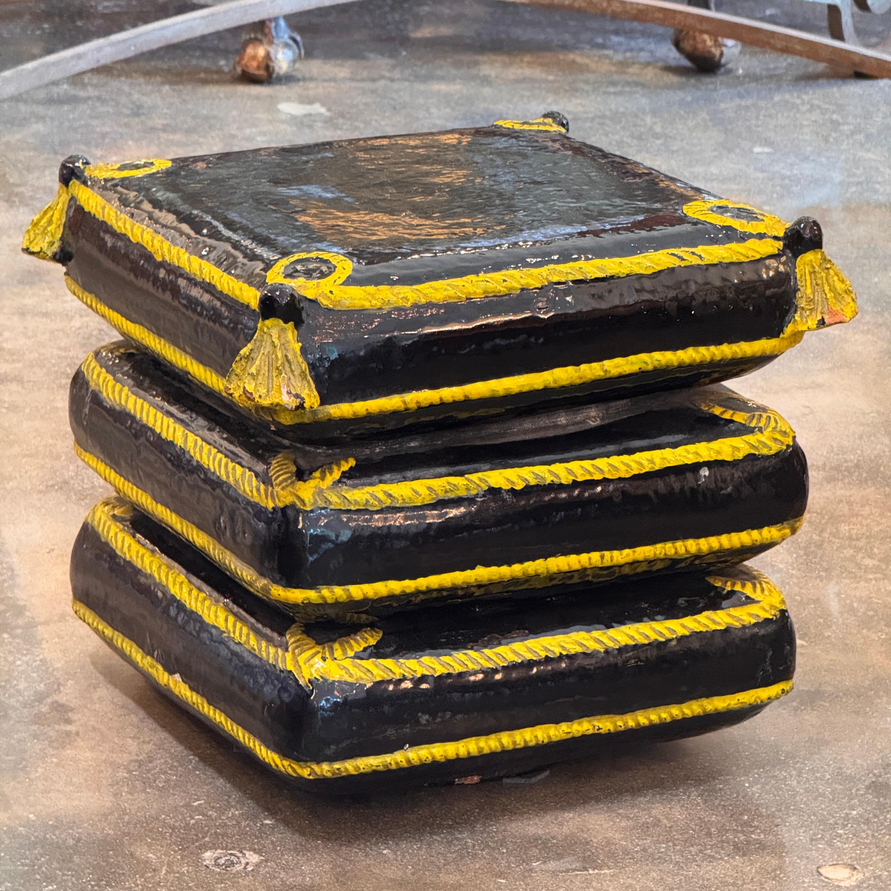 Handcrafted terracotta garden seat styled as three stacked tassel-trimmed cushions. Finished in a high-gloss black glaze with yellow rope detailing, this sculptural piece adds playful trompe-l’œil appeal to garden or indoor spaces