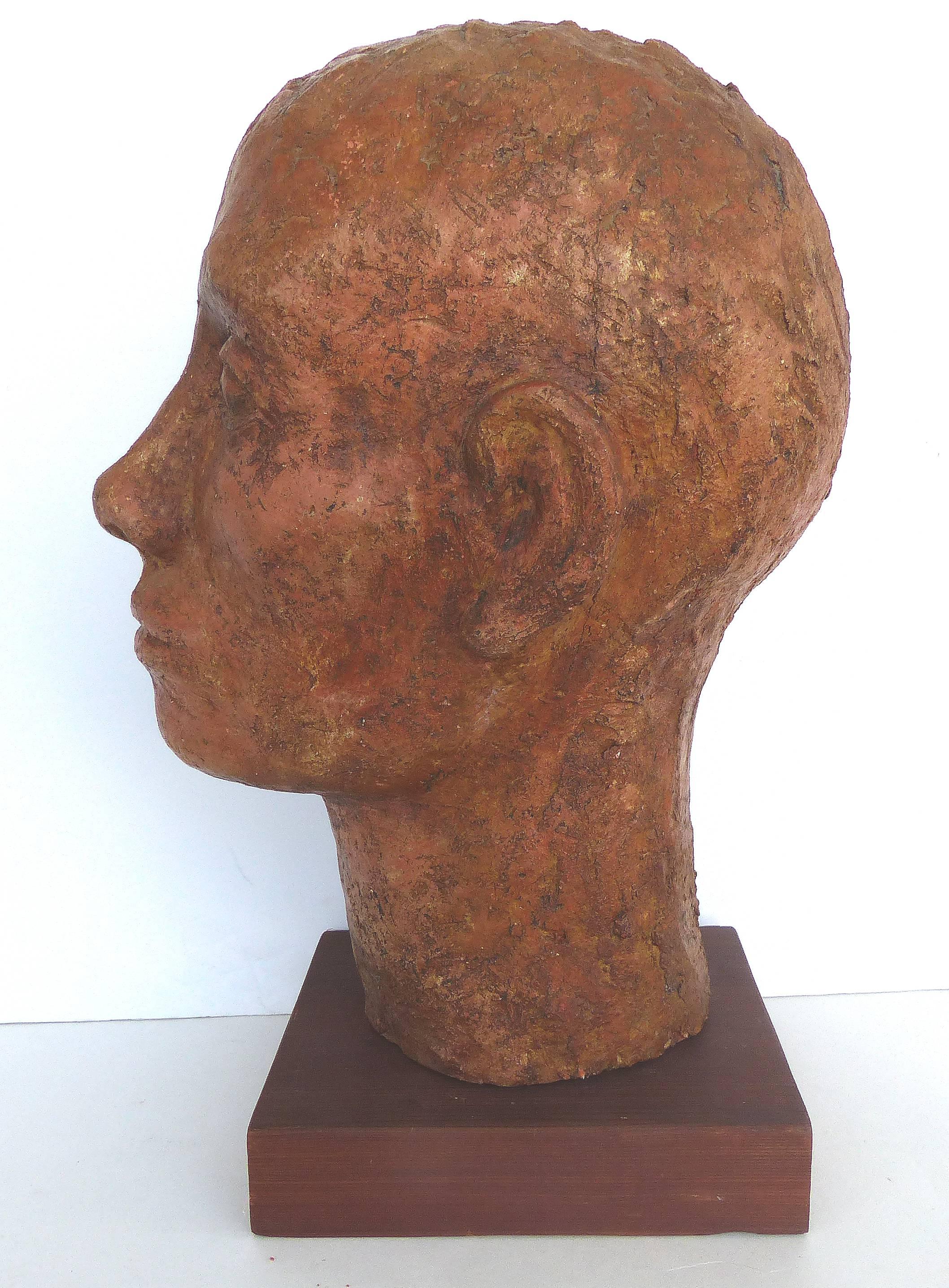 Terracotta Head Sculpture on a Wood Base

Offered for sale is a terracotta sculpture of a man's head which is illegibly signed on the bottom. The sculpture is rustic in nature with a textured finish. The sculpture rests upon a wood plinth which