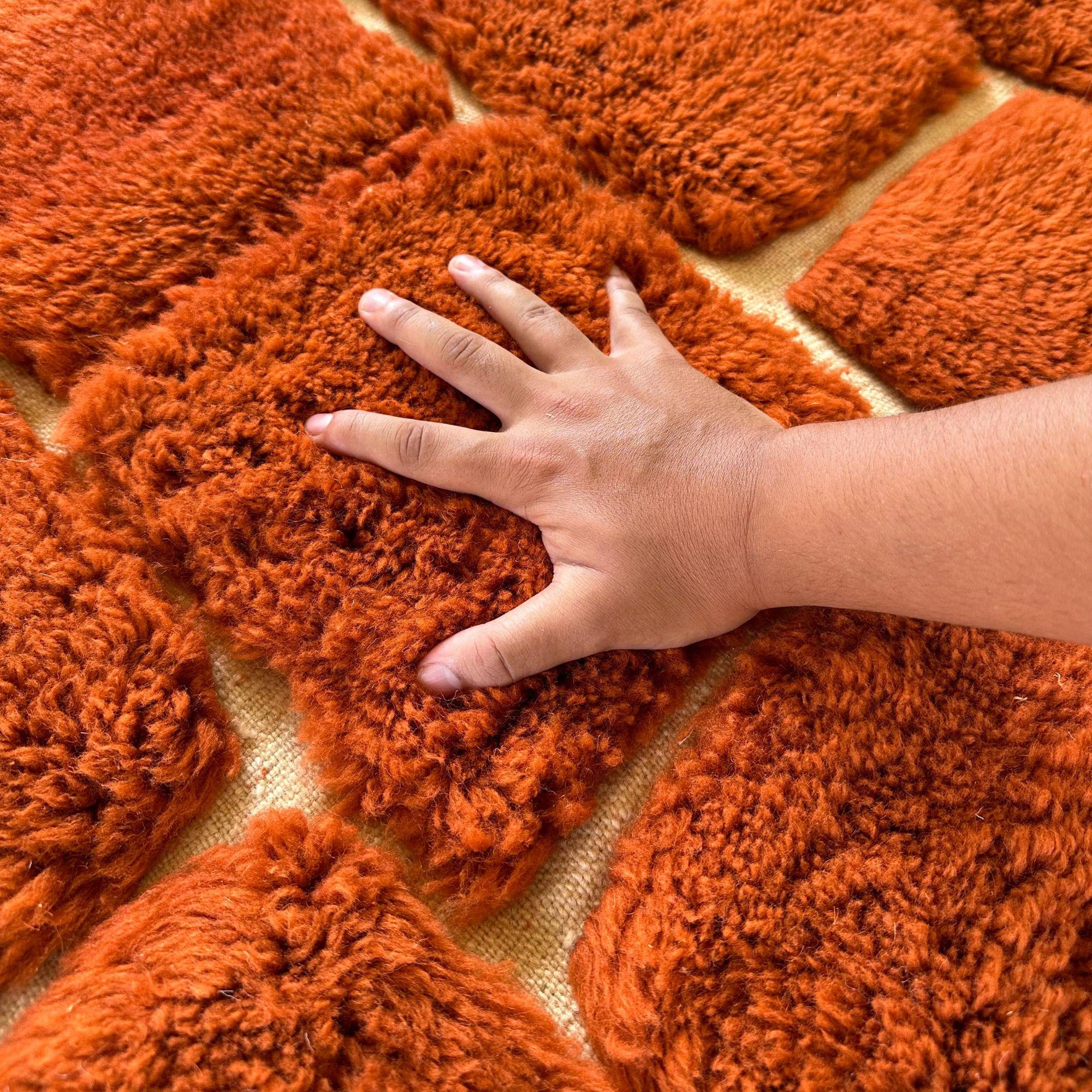 La Royal Nomadic es una lujosa alfombra marroquí de terracota que combina la artesanía bereber tradicional con elementos de diseño modernos. Esta obra maestra tejida a mano presenta un diseño a cuadros texturizado sobre una cálida base de terracota,