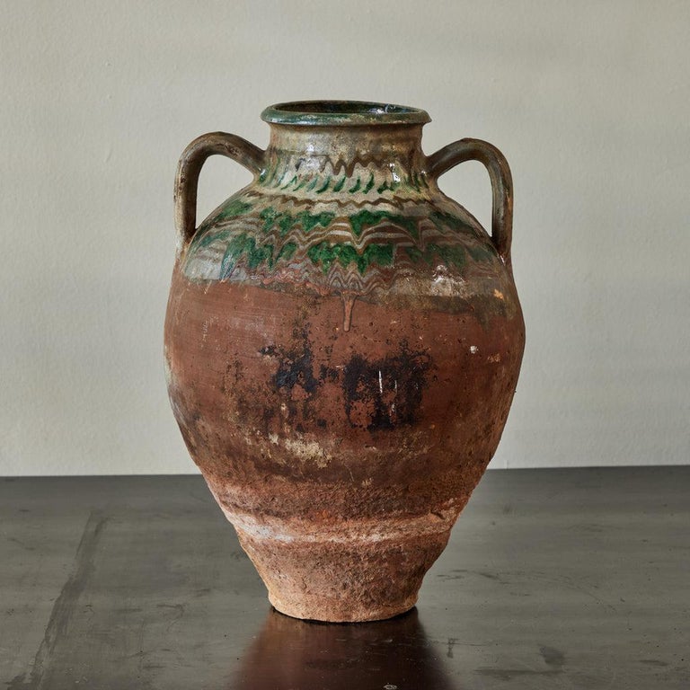 Turn-of-the century Bulgarian olive oil pot with green, white, and brown traditional drip-style glaze. The glazing on this amphora-shaped terracotta vessel has a free and relaxed, vaguely psychedelic quality. Could equally function as a vase, or as
