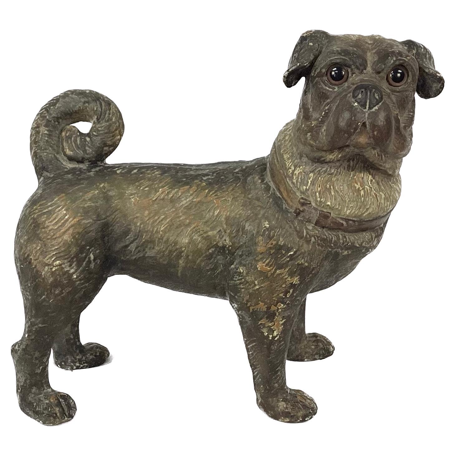 An exceptionally detailed standing terracotta pug dog with brilliant brown glass eyes. Pug has on a collar and it's tail is curved over it's back as is the breed standard. 