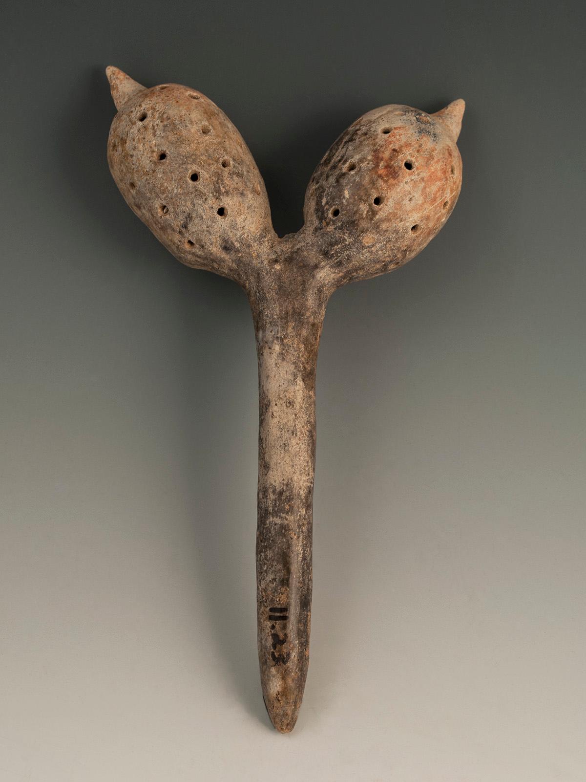 Circa 100 B.C. - 250 A.D. Terracotta rattle, Colima, West Mexico.

A forked rattle with a multitude of perforations over the bulbous pod-like bodies, having pellets inside for sound. No damage or restoration. Collection #11-23 can be seen on verso