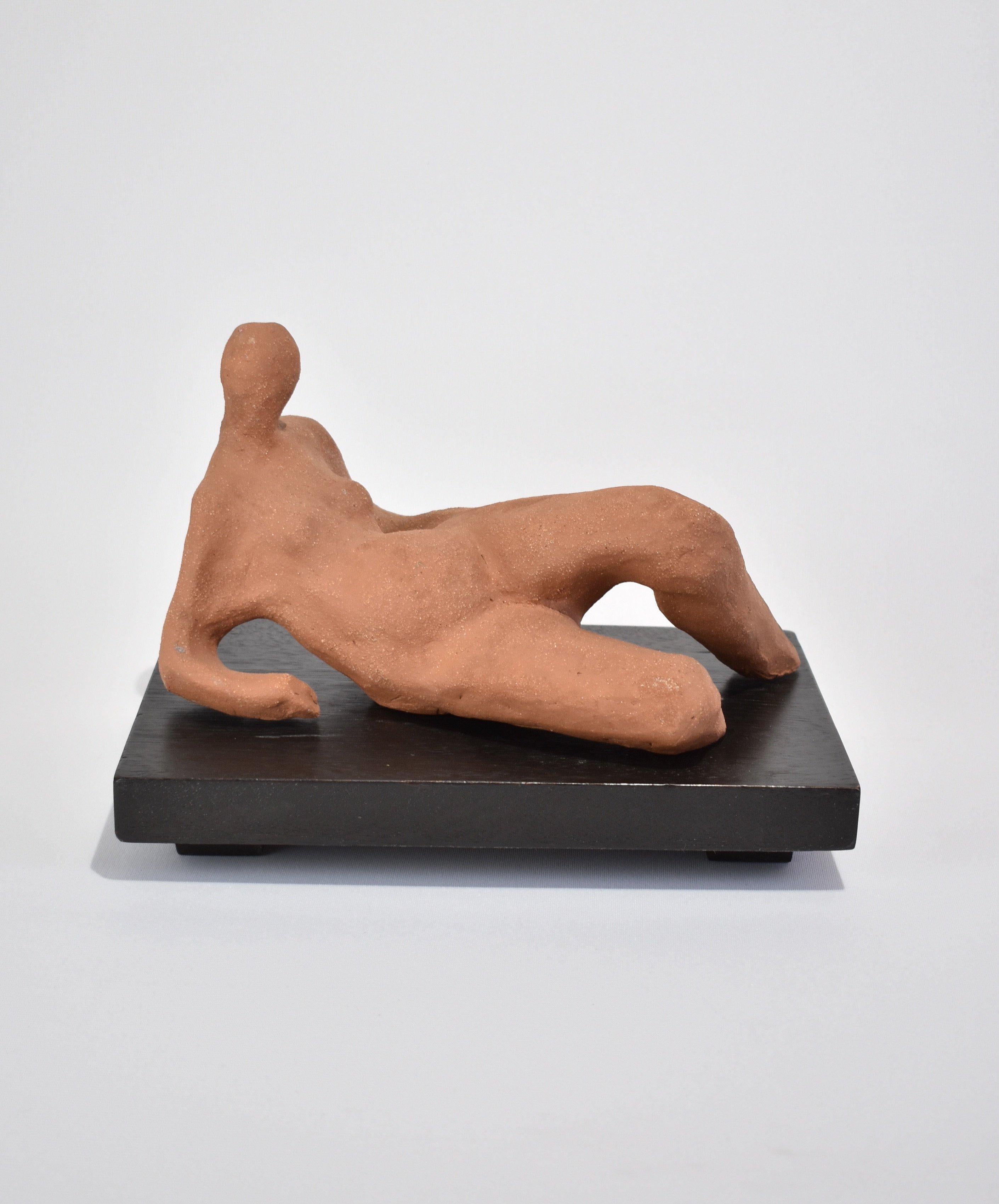 Stunning, terracotta figure sculpture on a detached black wooden base. Illegibly signed and dated on base. Reminiscent of Henry Moore's Reclining Figures.

Dimensions:
Sculpture, 11