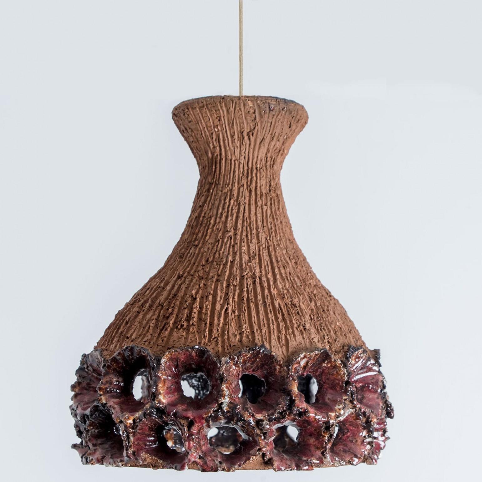 Elegante lampada a sospensione in ceramica realizzata in Danimarca. La lampada è realizzata in ceramica color terracotta e rossa e presenta grandi fori che creano una splendida illuminazione.

Un pezzo unico nella stanza.

Pulito, ben cablato,