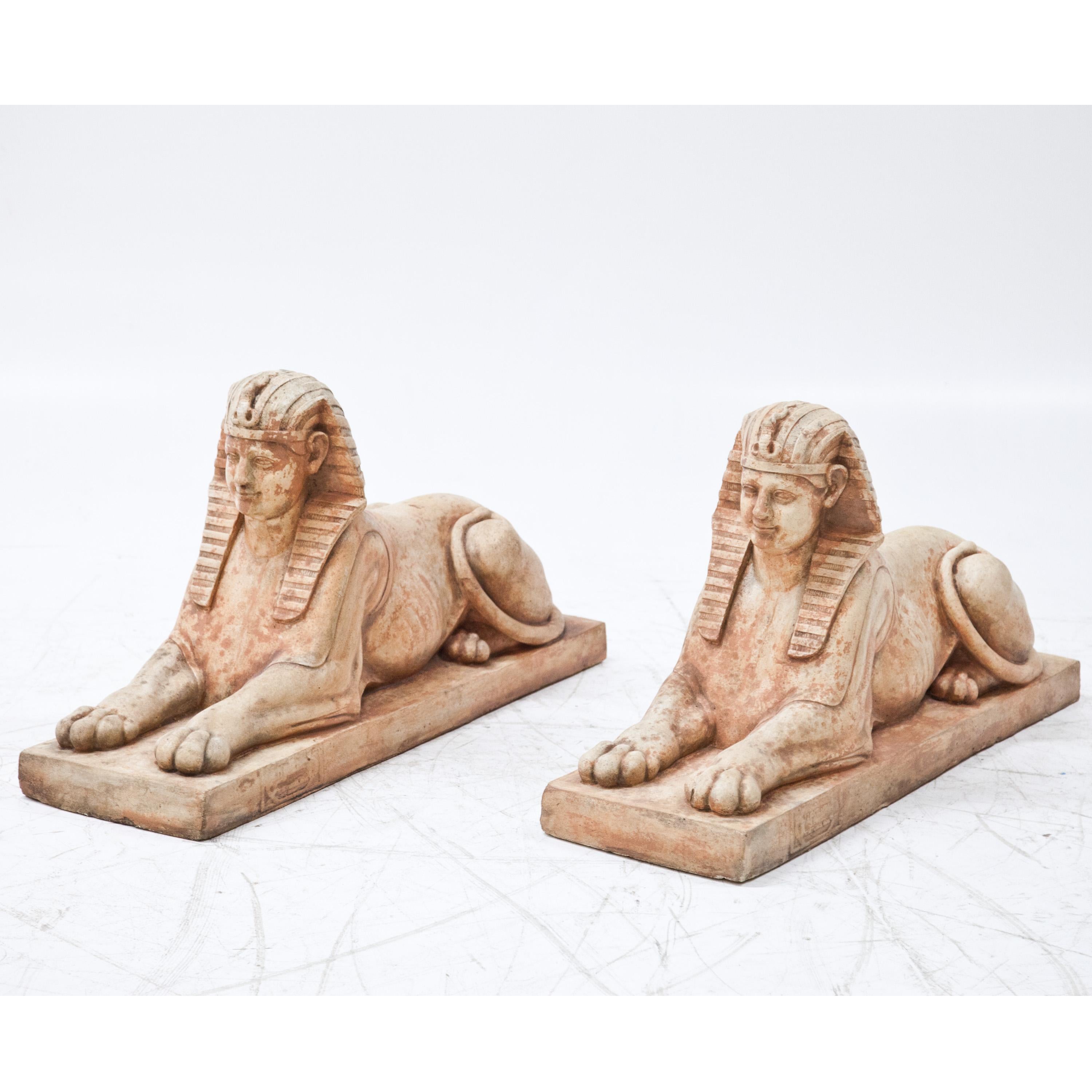 Pair of red patinated terracotta sphinxes on rectangular pedestals.