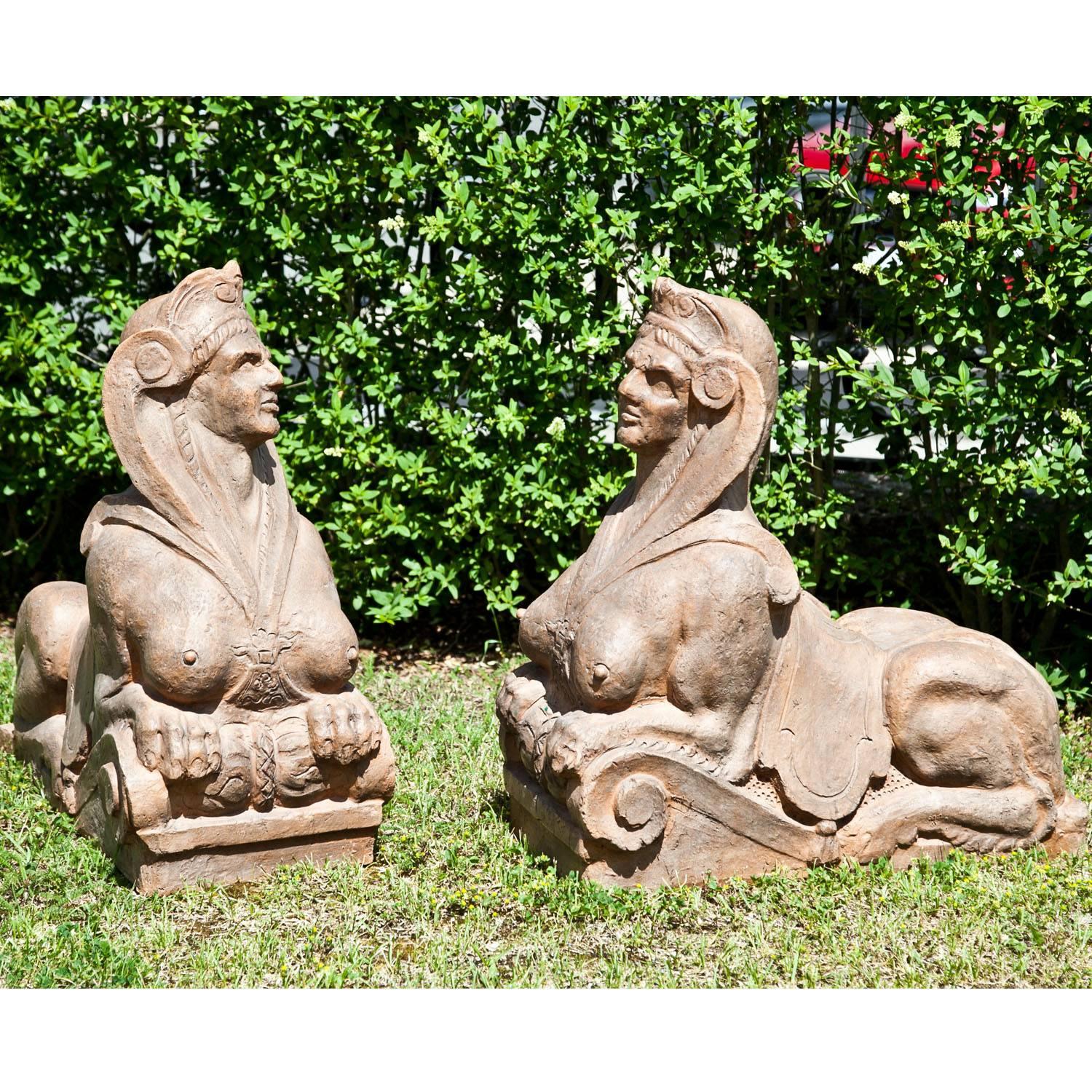 Pair of large erotic terracotta sphinxes, resting their front legs on a volute base.