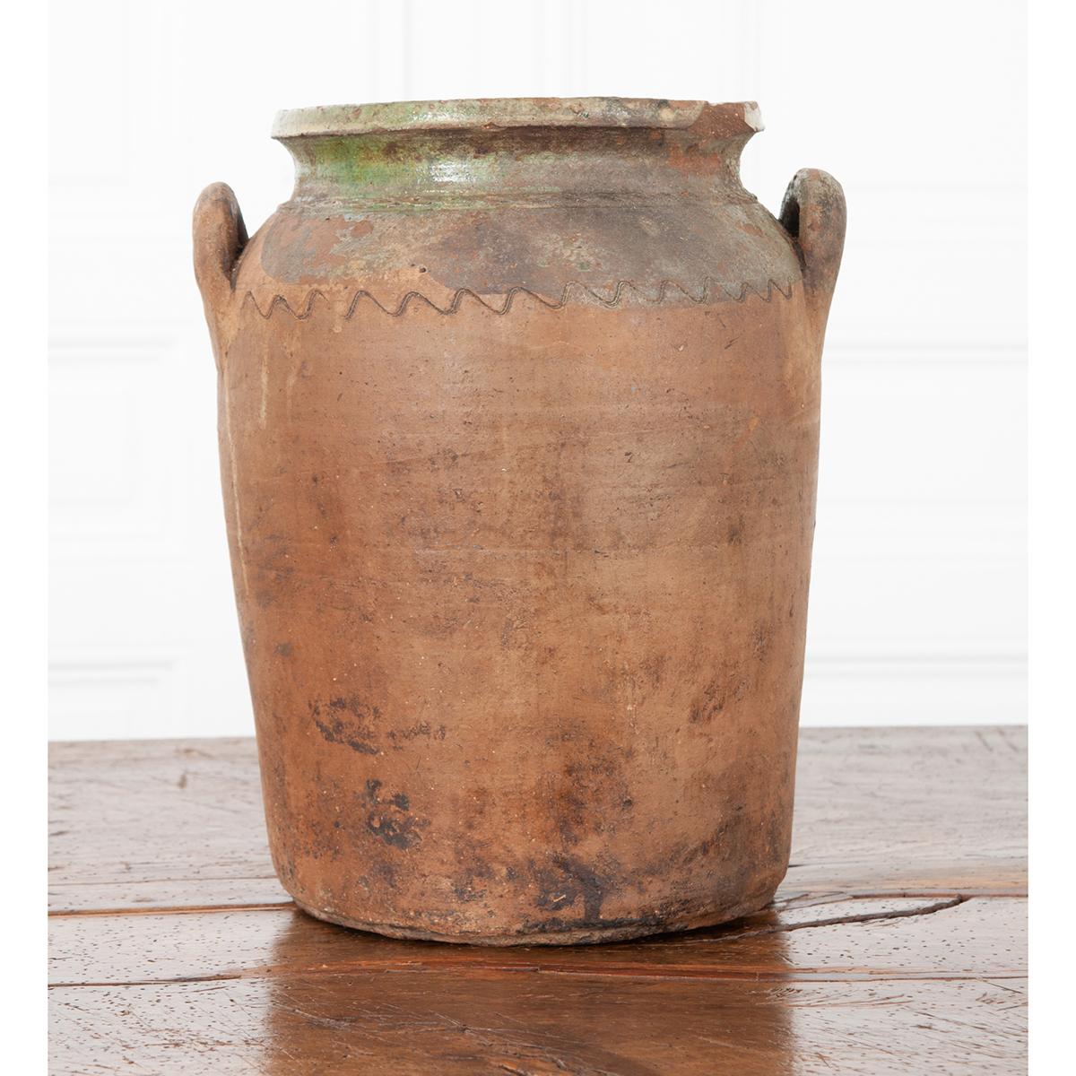 This wide-mouth terracotta vase is one of a kind. With a worn partial green glaze at the top and carved wavelike details, this storage jar will add the perfect provincial look to any indoor or outdoor space. Two handles on the side of the jar are