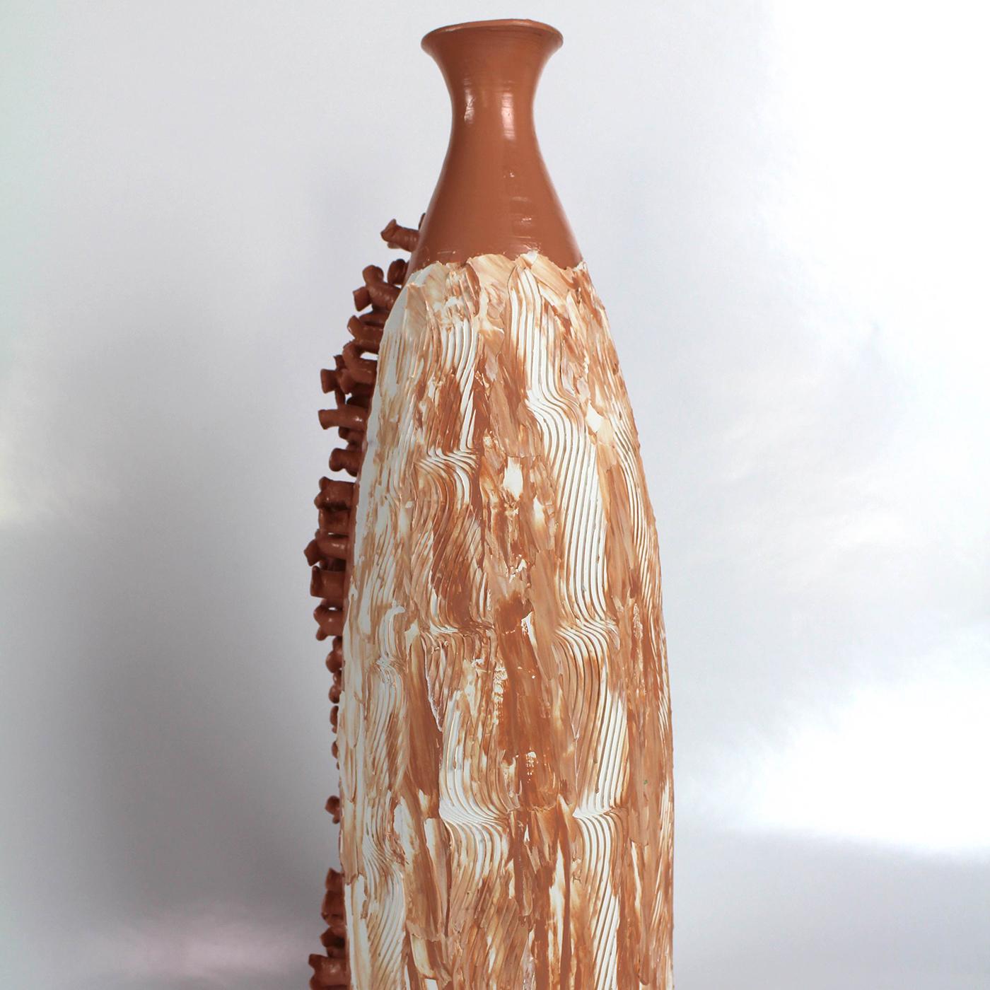 This beautiful vase by designer Mascia Meccani is crafted from red terracotta. Its slender silhouette with tapered neck is hand-embellished, painted in a pretty pink tone and adorned with unusual textured detailing. Exuding a wonderfully rustic