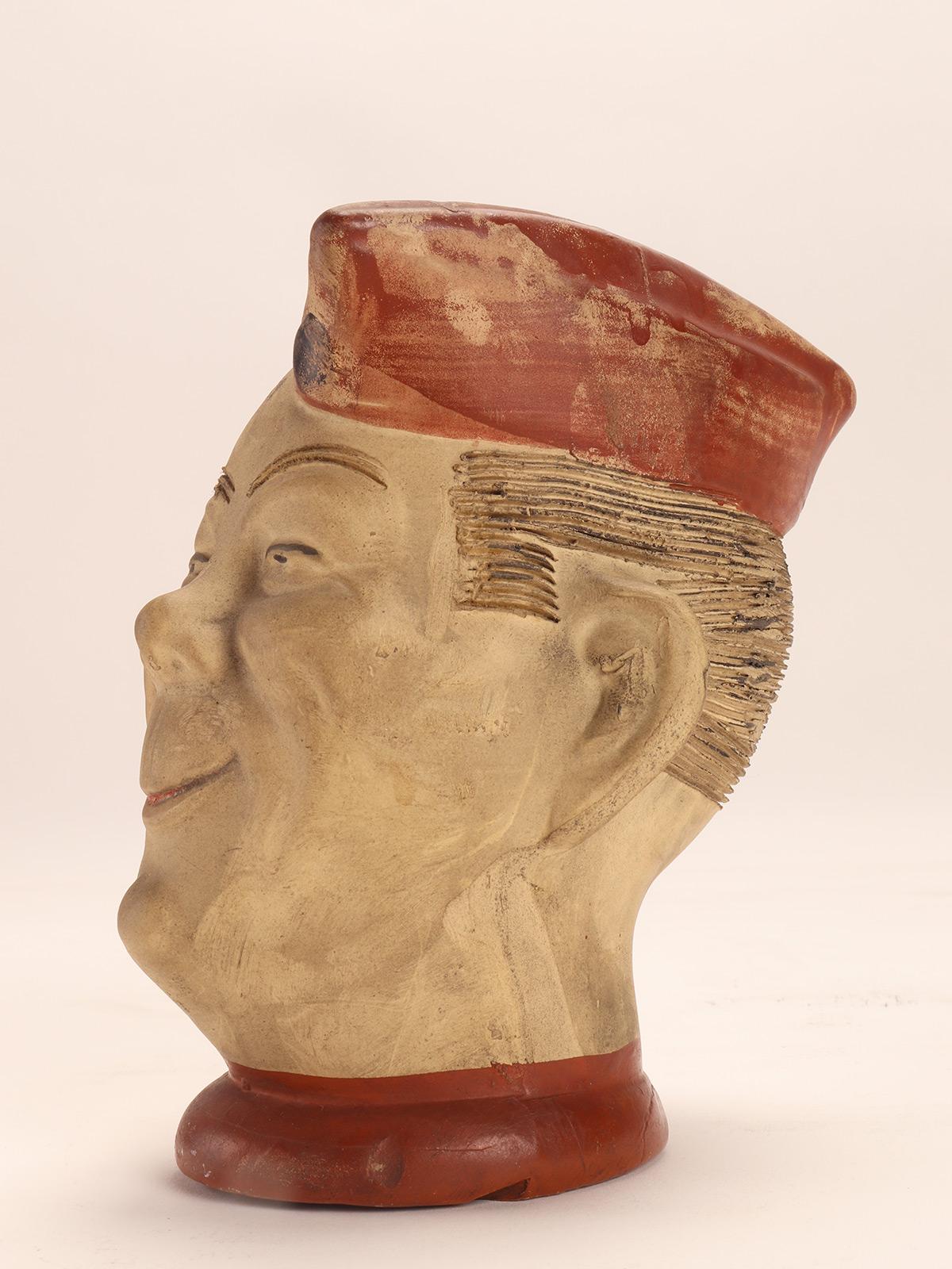 Unglazed terracotta pottery vase, by Elmer Early Chia Pet, depicting a soldier's head from the Second World War, wearing a red hat. Made by Robinson-Ransbottom Pottery Company in Ohio, USA in the 1940's.