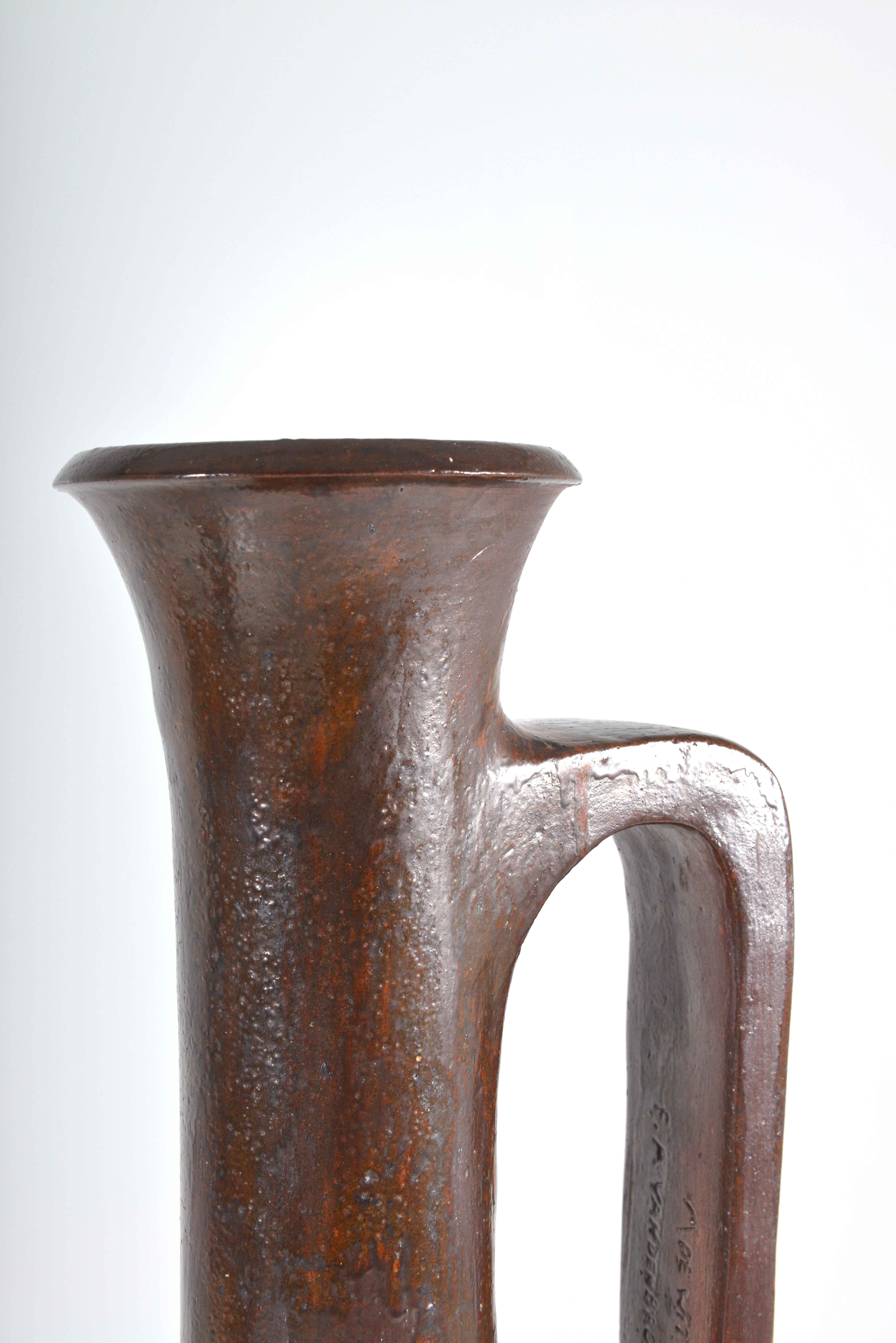 This almost life-size late 1960s vase is made of rough terracotta. It’s a very elegant and extremely tall vase. It’s a surreal updated version of the Greco-Roman tradition and color scheme. The feeling is Mediterranean and does remind of the plain