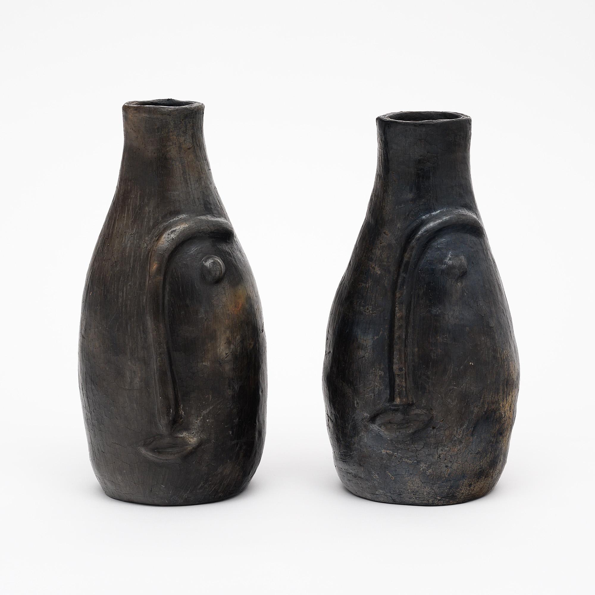 Pair of vases, French, of pigmented terra cotta. The vases are hand made in the tradition of Vallauris, on the French Riviera. The vases boast stylized Modernist facial features and a beautiful patina.