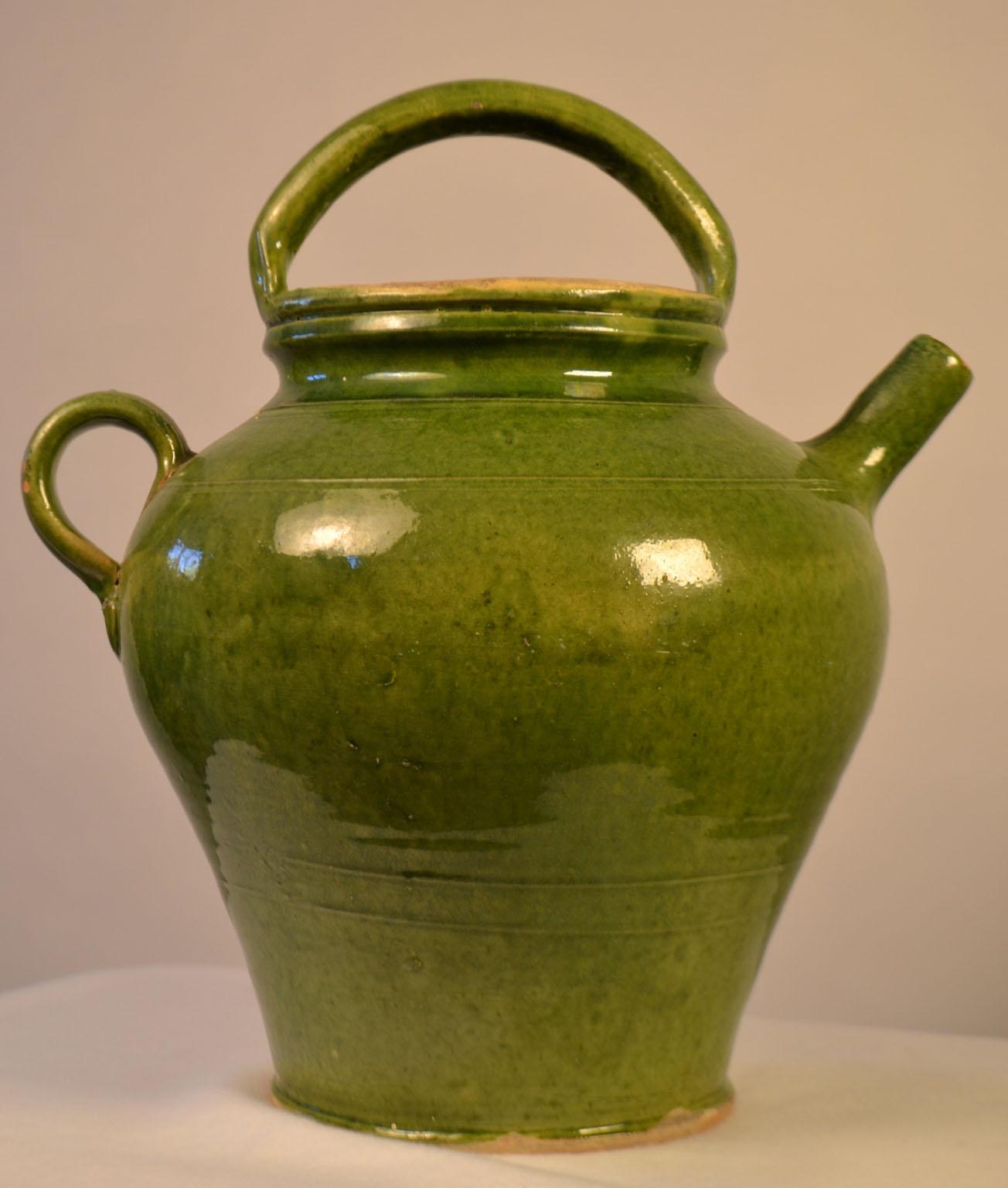 Turn of the century (circa 1900) terracotta water jug with a nice deep green glaze. Minor glaze scale and skips.Once a common piece of pottery used daily in French kitchens, these earthenware jugs have become showcase pieces sought by designers and