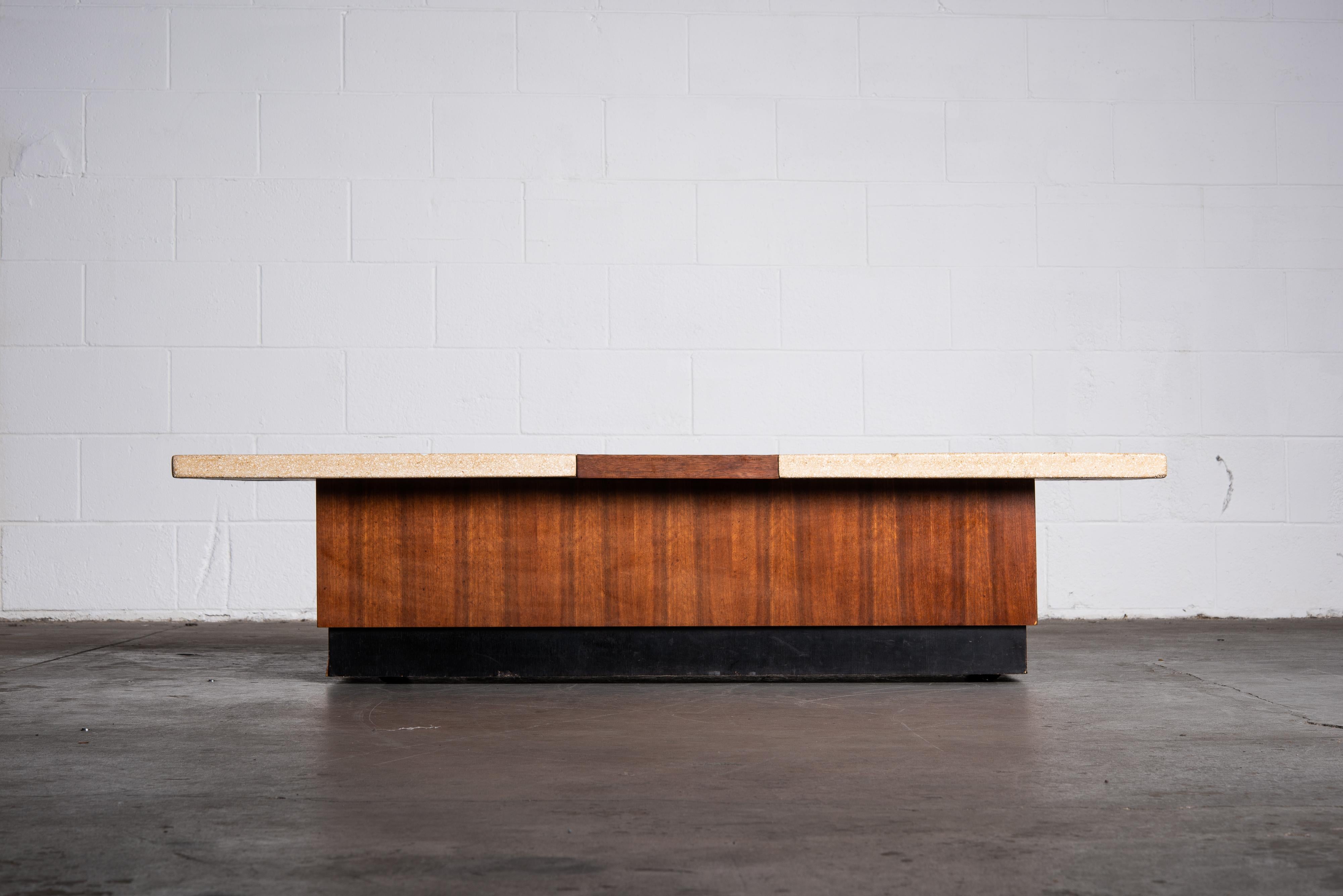 A stylish Mid-Century Modern Terrazzo and Walnut coffee table or bench in the style of Harvey Probber, featuring two terrazzo stone tops with a walnut section in between, on top of a walnut and ebonized plinth base with hidden casters to make it
