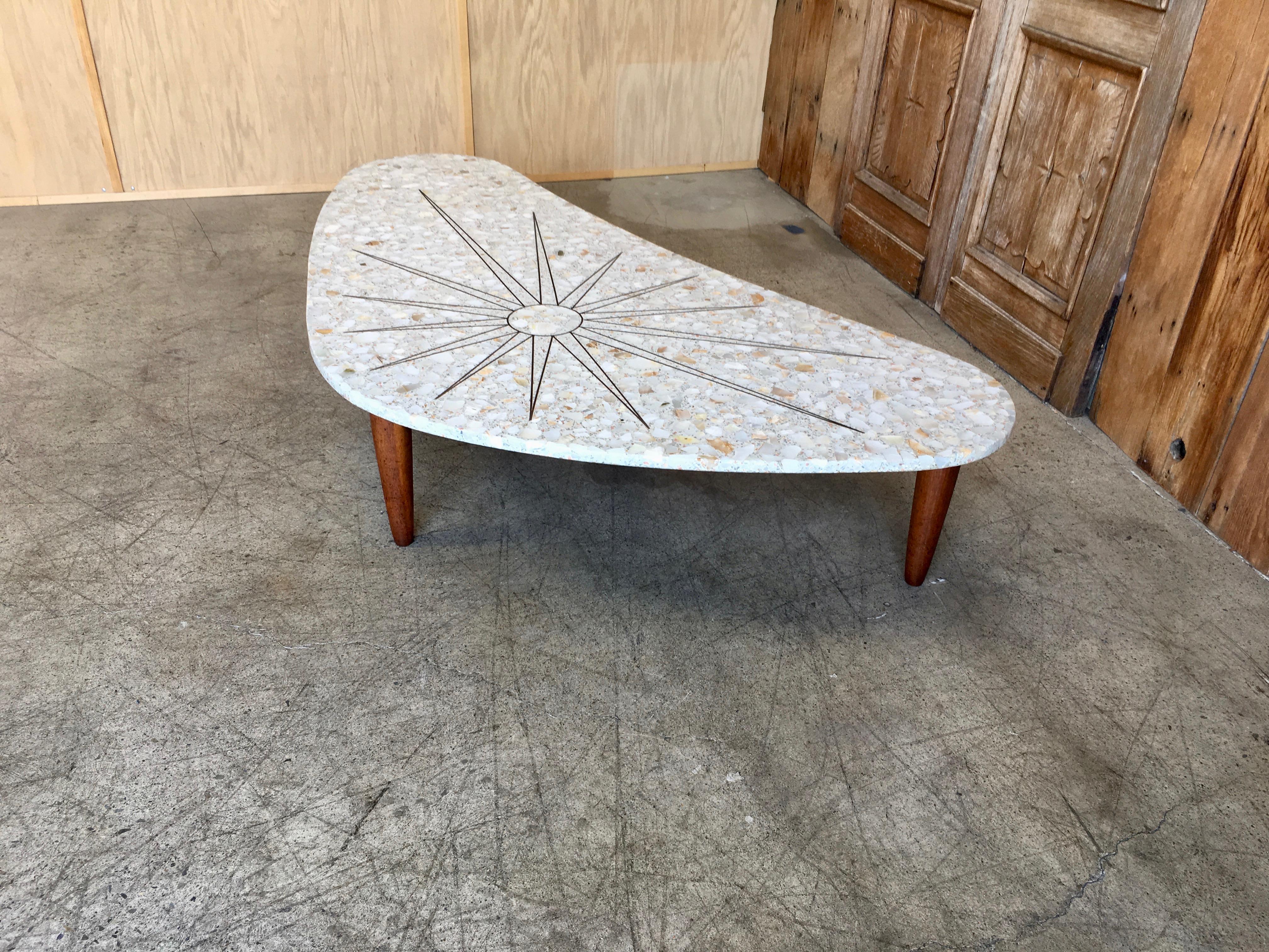 Massive coffee table with Italian walnut legs and a kidney shaped terrazzo top with brass inlaid sunburst.