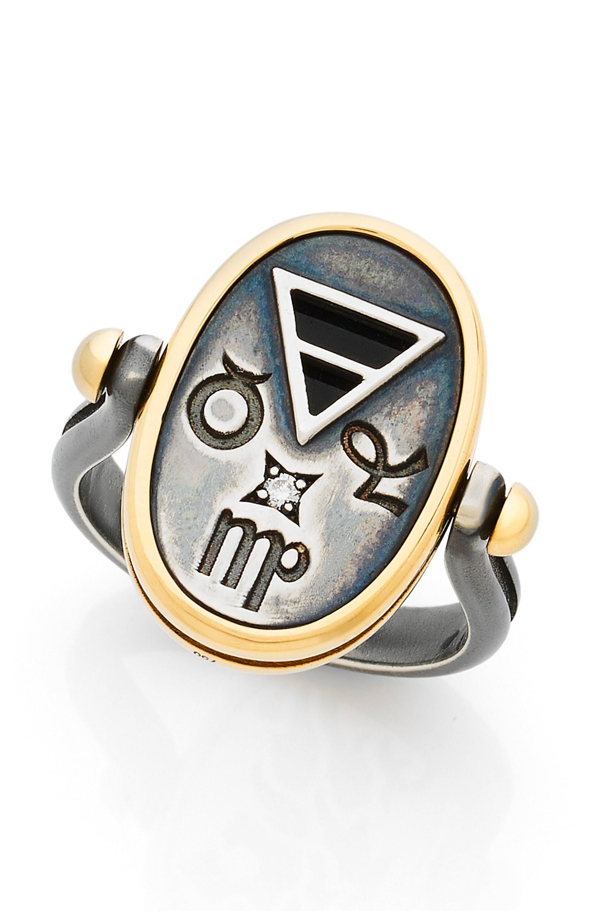 Gold and distressed silver ring. On one side, encrusted with a diamond, are engraved Earth signs (Virgo, Capricorn, Taurus). On the other side is an openwork depicting a lion on an onyx base. 

Details:
Diamond: 0.015 cts
18k Yellow Gold: 4