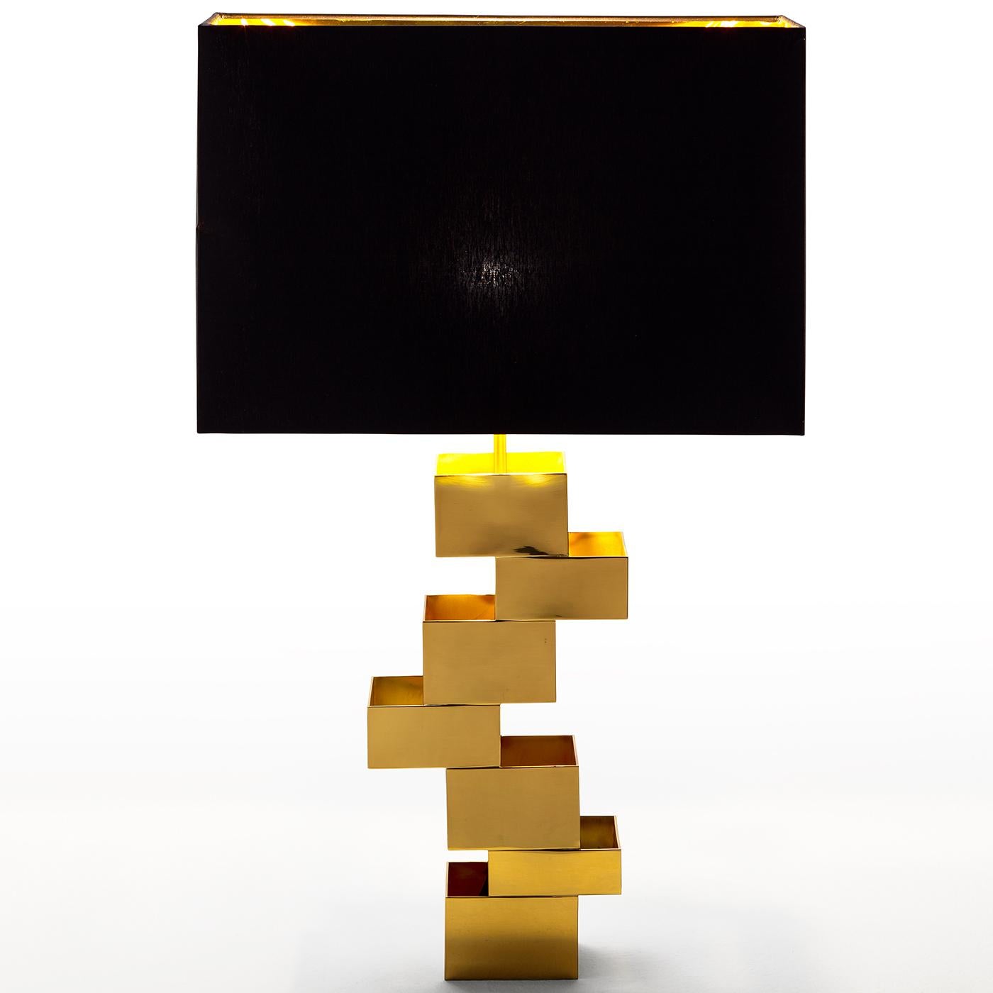 Cette lampe de table est une œuvre d'art sculpturale qui se caractérise par un jeu d'équilibre fascinant. Son design saisissant se caractérise par un abat-jour rectangulaire noir qui émettra une lumière diffuse et dorée grâce à son intérieur