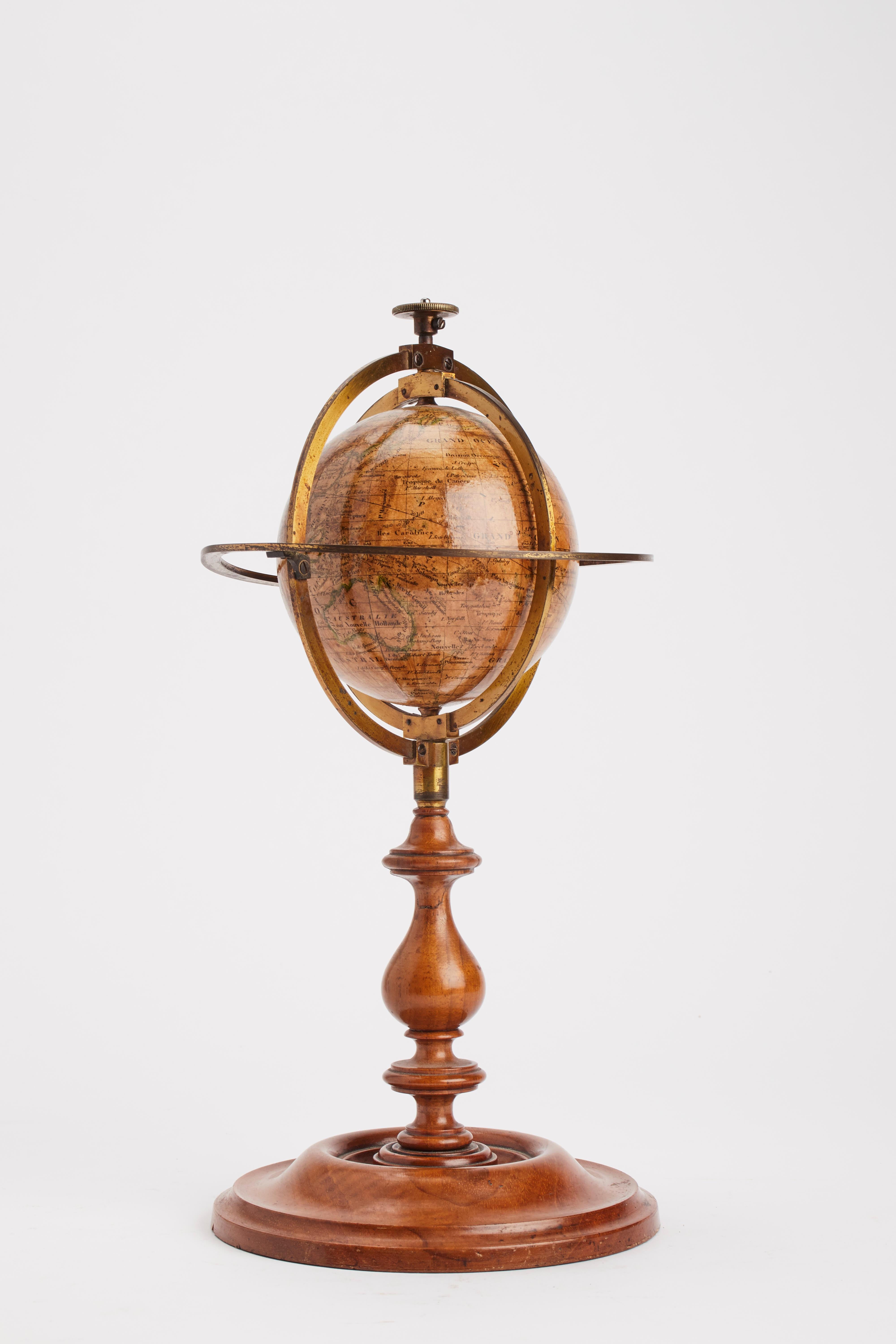 A small terrestrial globe, papier mâché, caged into a brass armillary structure, with tall foot and mahogany wooden base. Signed Delamarche, Paris, France, 1864.