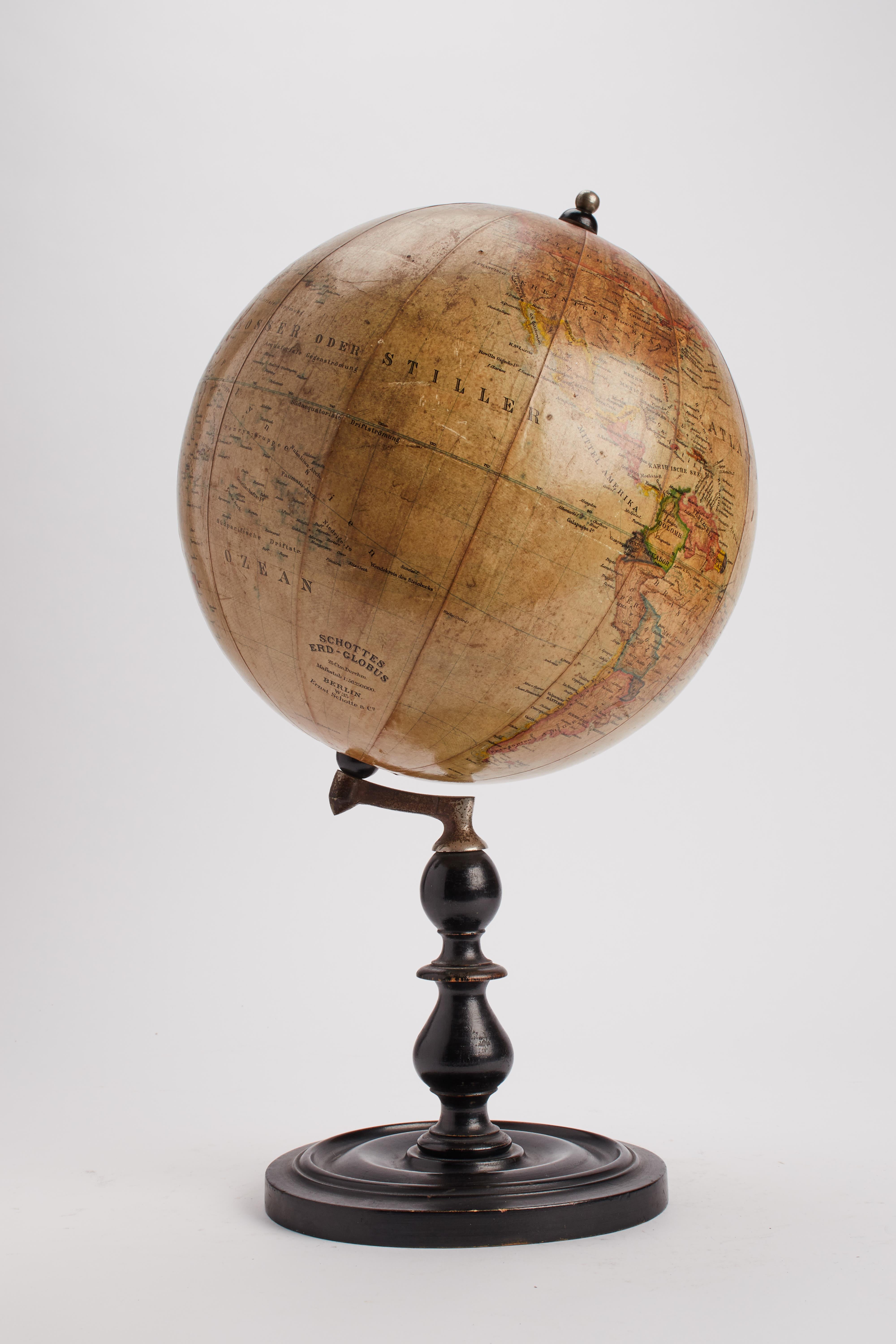 Terrestrial globe in watercolored paper, fixed with an inclined axis through a small brass arm, mounted on a black turned fruit wood base. Published by Ernst Schotte & Co. Berlin, Germany late 19th century.