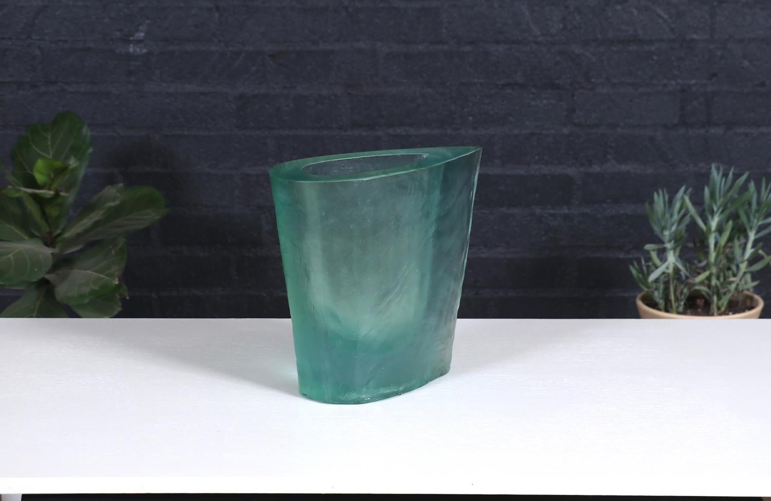 This striking Post Modern resin vase by Terry Balle is a sculptural masterpiece that challenges traditional design norms. Cast in a translucent seafoam green hue, its asymmetrical form and soft, organic edges create an almost fluid appearance. The