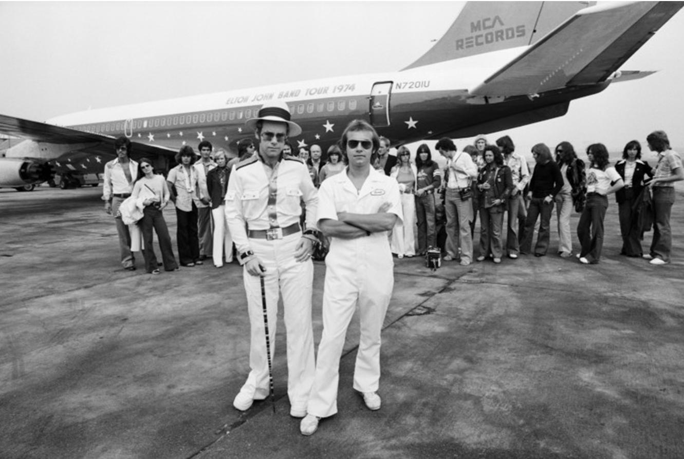 Elton John is photographed in front of his private Boeing 720 plane "The Starship" on an airport runway in California. The photo was taken before John and his team left for the remainder of his US tour in 1974.

Signed limited edition, hand printed
