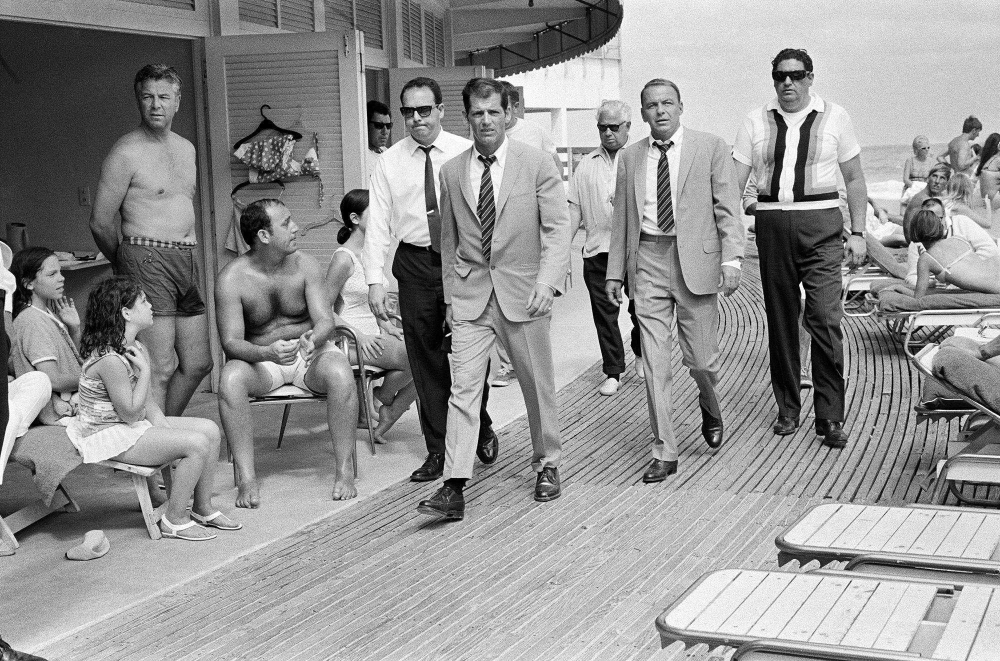 Terry O'Neill Black and White Photograph - Frank Sinatra with his Stand-In and Bodyguards Arriving on Location, Miami Beach