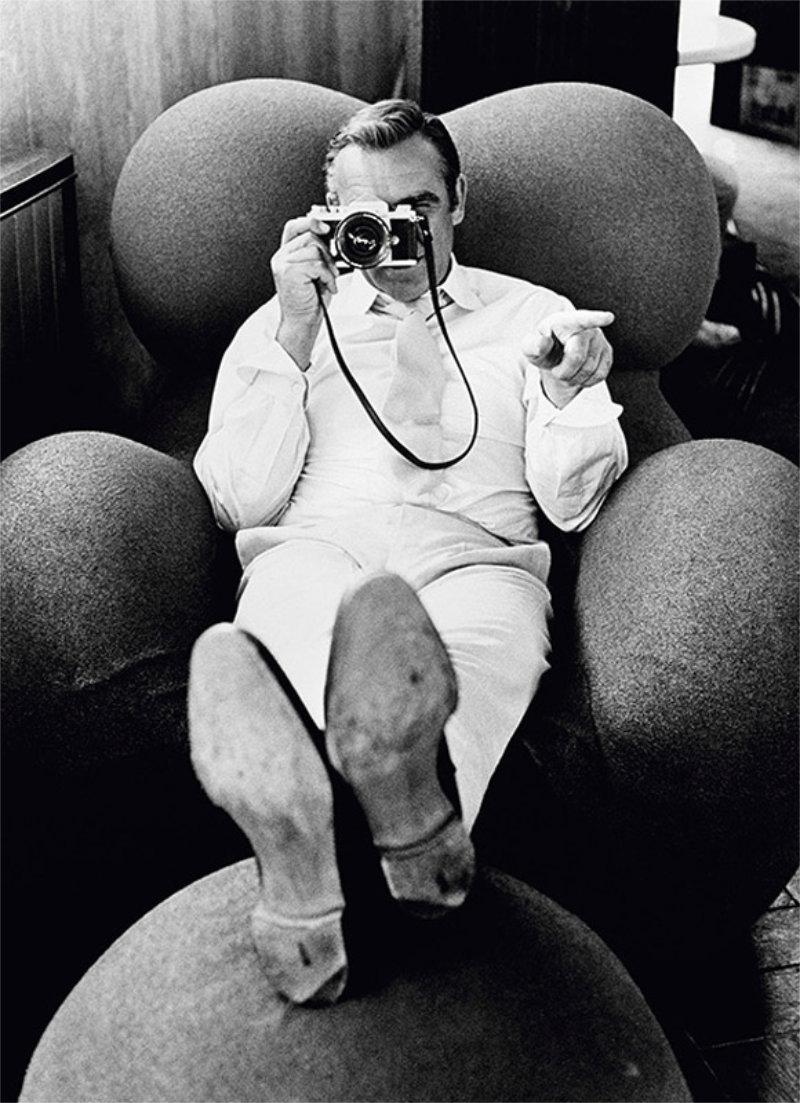 Terry O'Neill Portrait Photograph - Sean Connery - the actor sitting on sofa with camera in is hand 