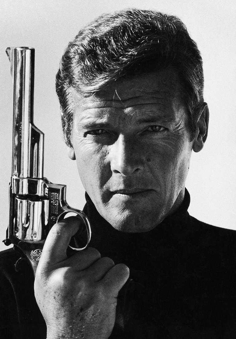 Der britische Schauspieler Roger Moore posiert als James Bond mit einer Waffe. Werbeaufnahme von 1973 für seinen ersten Bond-Film: Leben und sterben lassen. Es ist das einzige Mal, dass Bond diese Art von Waffe, eine Smith & Wesson Model 29,