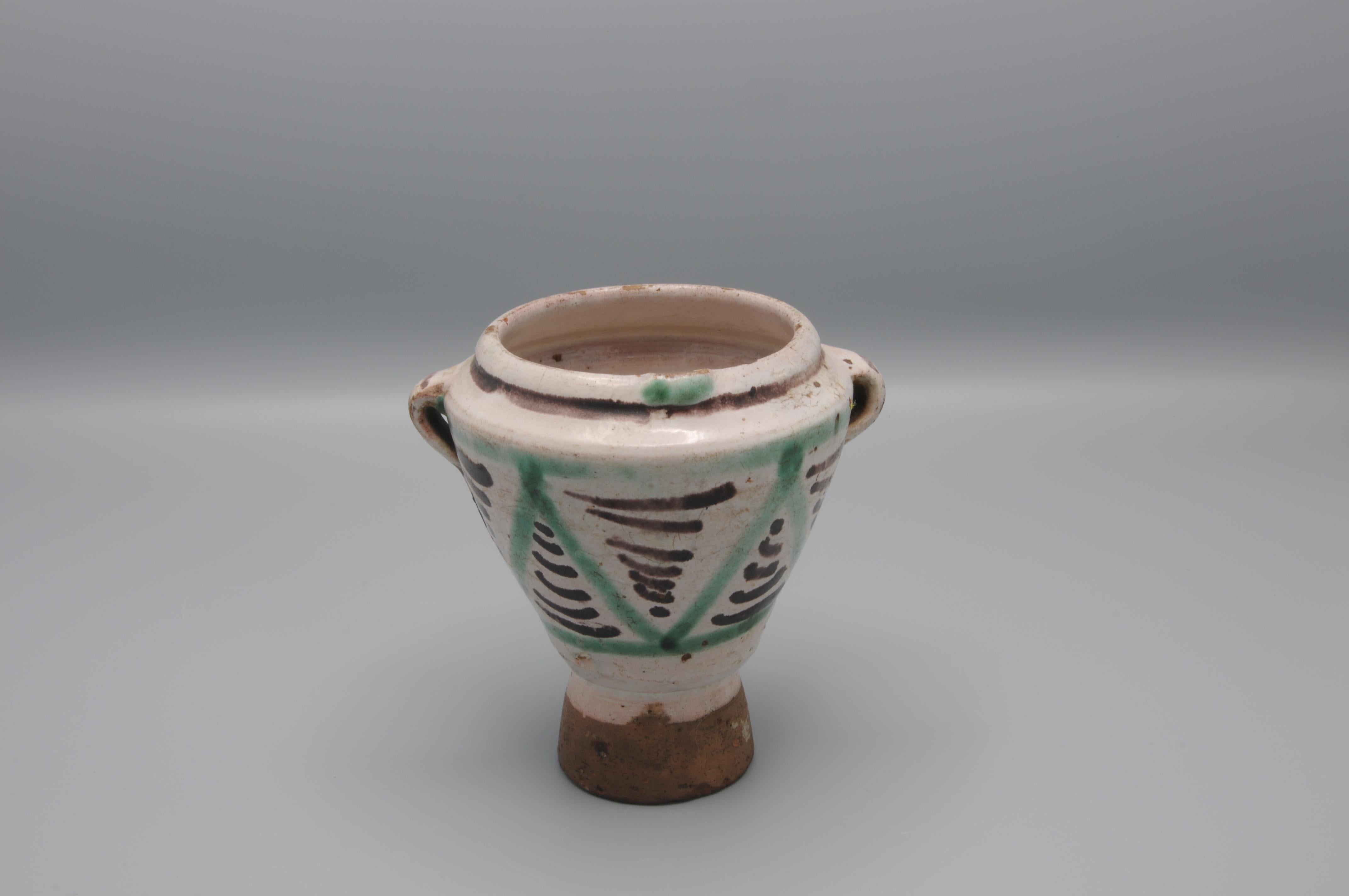 Ceramic mortar produced at the Teruel pottery workshops in the 17th century.
It has a truncated cone shape with three handles and a pourer. It is tin-glazed in a milky white, except for the unglazed foot. It is also decorated with green and