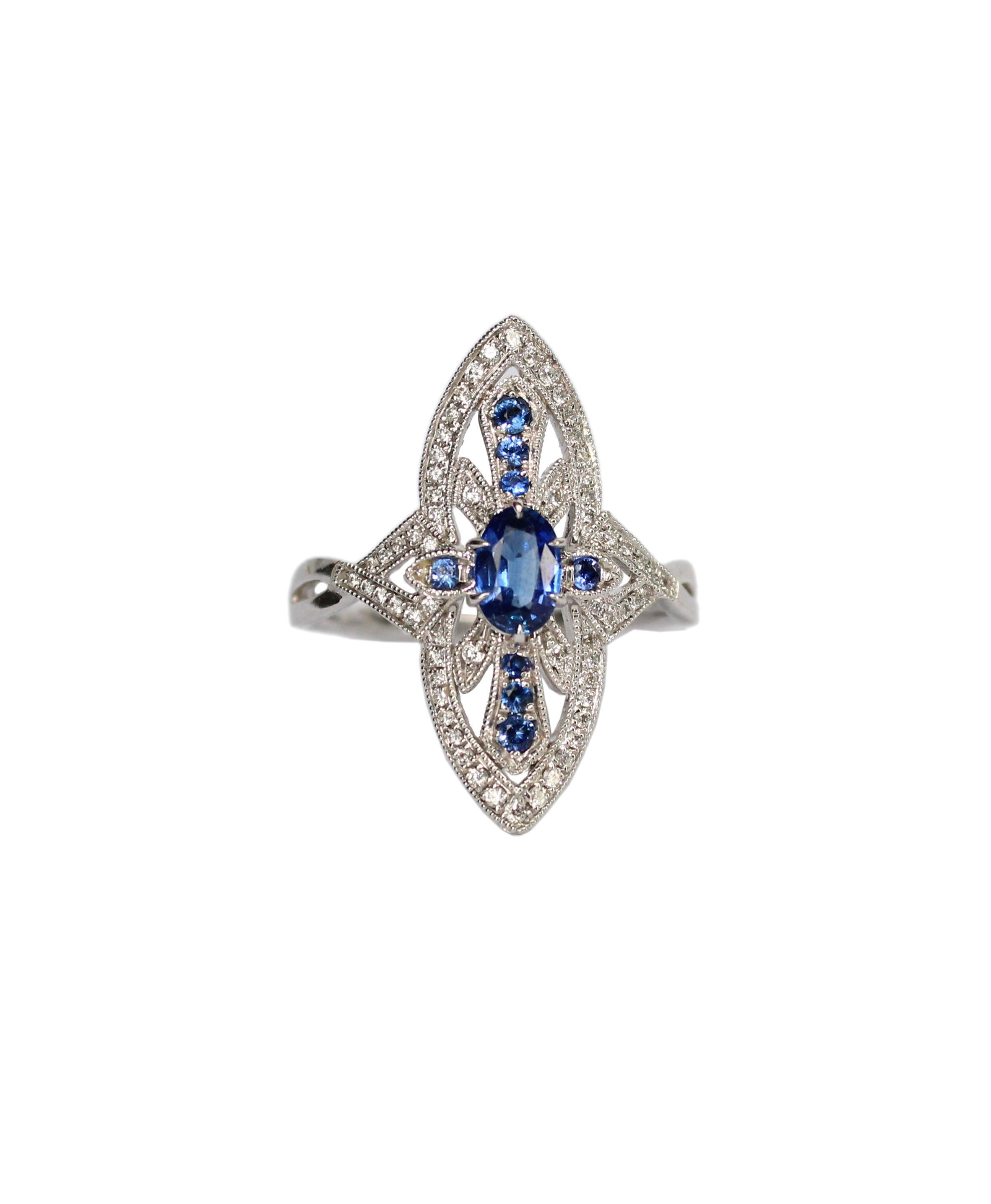 Art-Deco inspired 18K white gold ring by Tess Van Ghert London. The delicate ring is meticulously set with round diamonds and blue sapphires.

18KW 3.77 GM
8 Round Sapphires - 0.13 CT 
64 Round diamonds - 0.18 CT
1 Oval Sapphire - 0.52 CT

Comes
