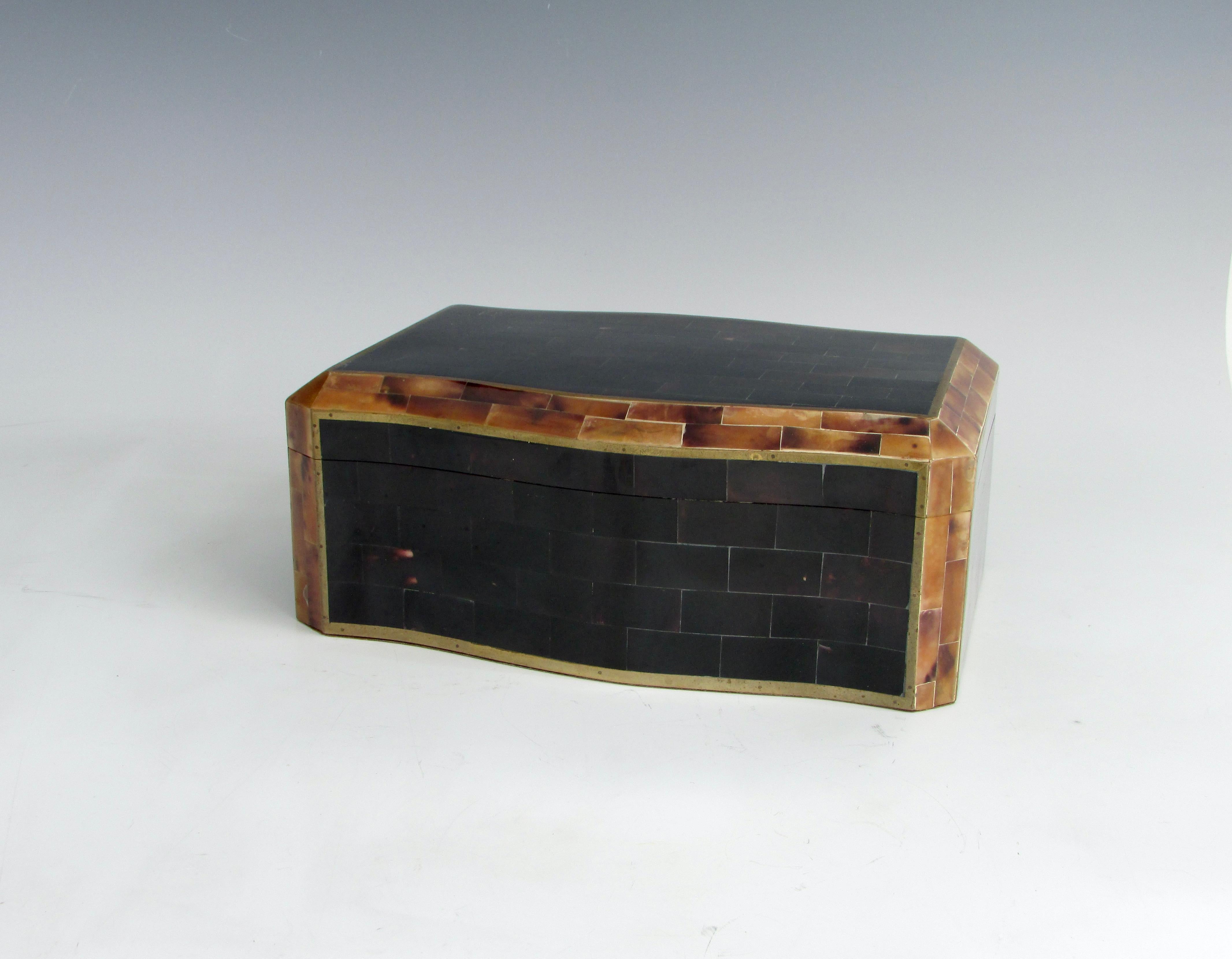 Elegante cassettiera rivestita in legno con coperchio a cerniera. Esterno in finto corno tessalato con finiture in ottone. Gli interni sono rivestiti in Wood. Conserva l'etichetta Maitland Smith.