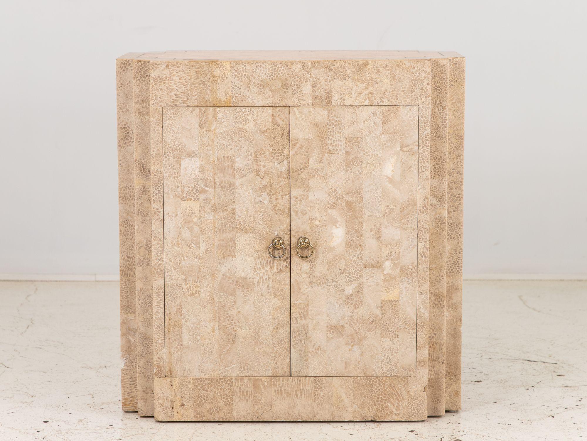 This tessellated travertine two-door cabinet exudes timeless elegance, reminiscent of Maitland-Smith's distinctive design aesthetic. Crafted with meticulous attention to detail, it showcases a harmonious blend of luxurious materials and masterful