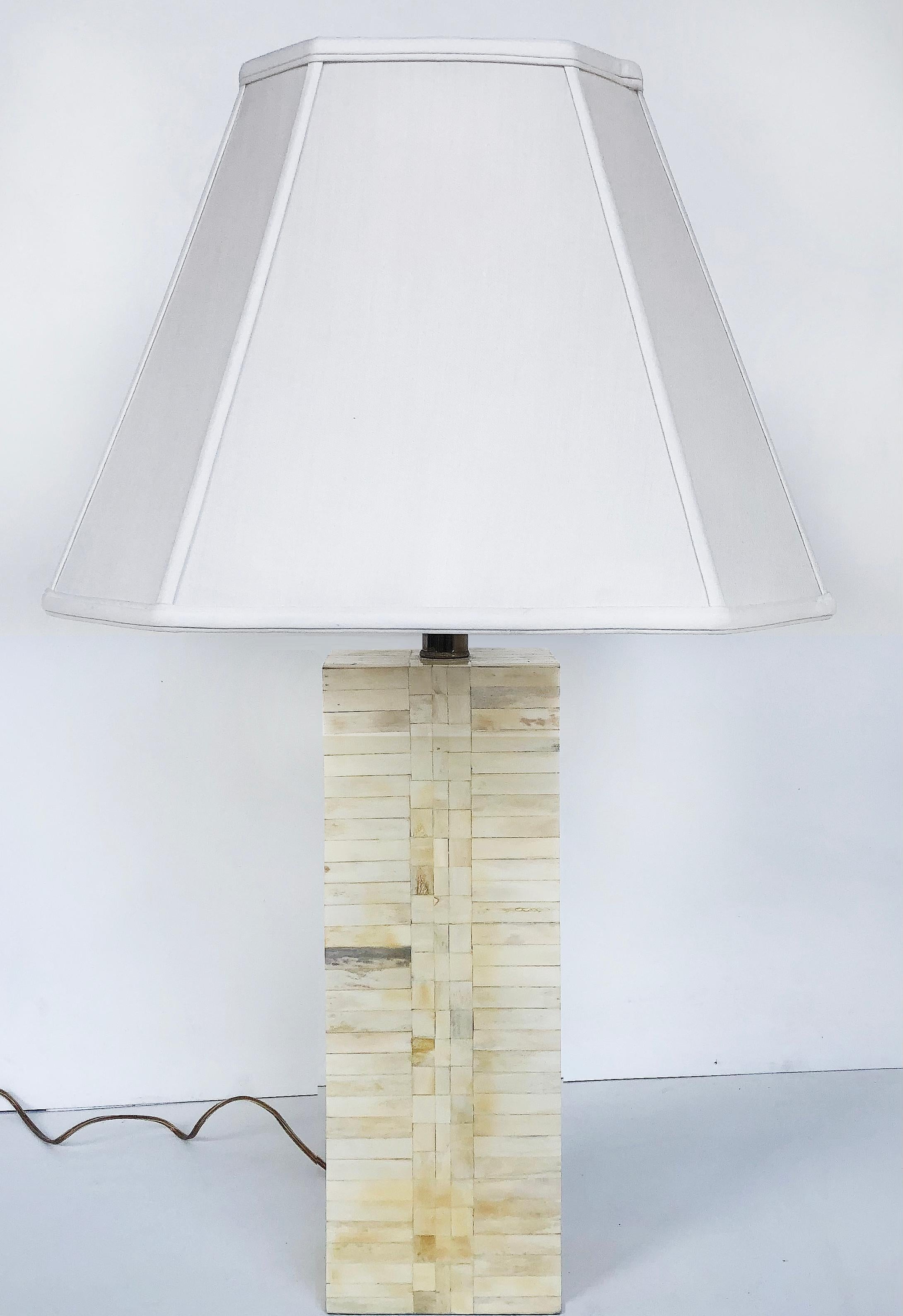 Offered for sale is a pair of Tessellated bone table lamps attributed to Maitland-Smith. The pair of lamps are completed with a pair of square fabric shades. The lamps each accommodate a single standard bulb. They are wired and working.