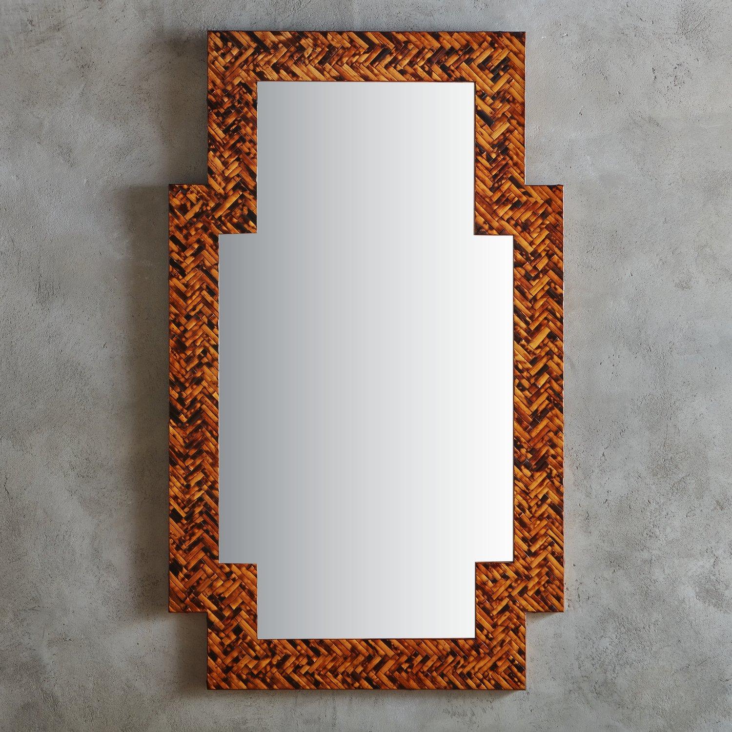 A large-scale 1980s wall mirror by Harrison Van Horn featuring a rectangular notched wooden frame clad in herringbone tessellated bamboo. The frame has a gorgeous range of cognac and amber hues and supports a delicately etched banded mirror. Retains